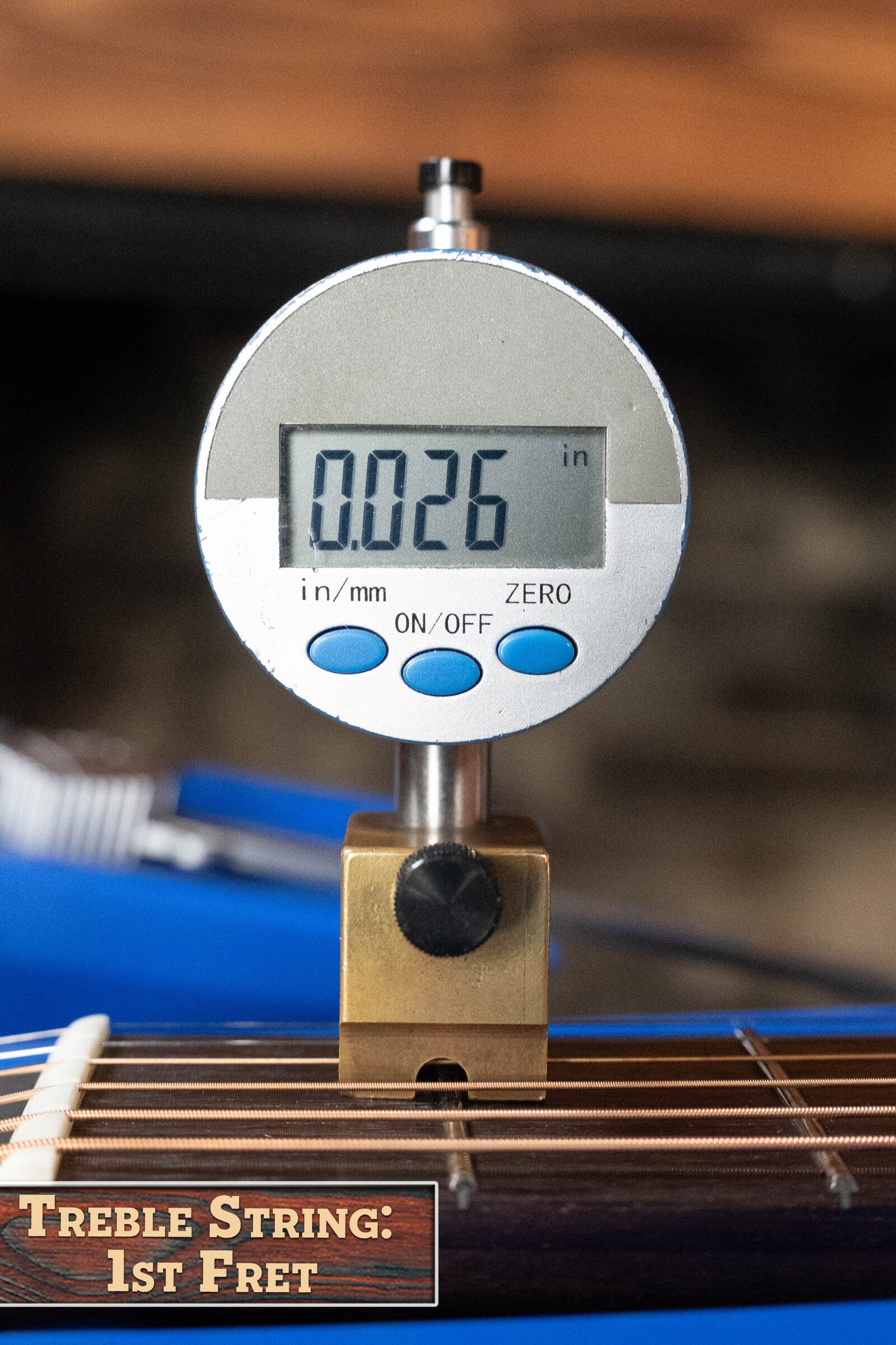 A digital caliper reads 0.026 inches for string height at the first fret of an Eastman PCH2-TG Thermo-Cured Solid Sitka/Laminated Rosewood Travel Acoustic Guitar #9714 by Eastman Guitars, with a label: Treble String: 1st Fret.
