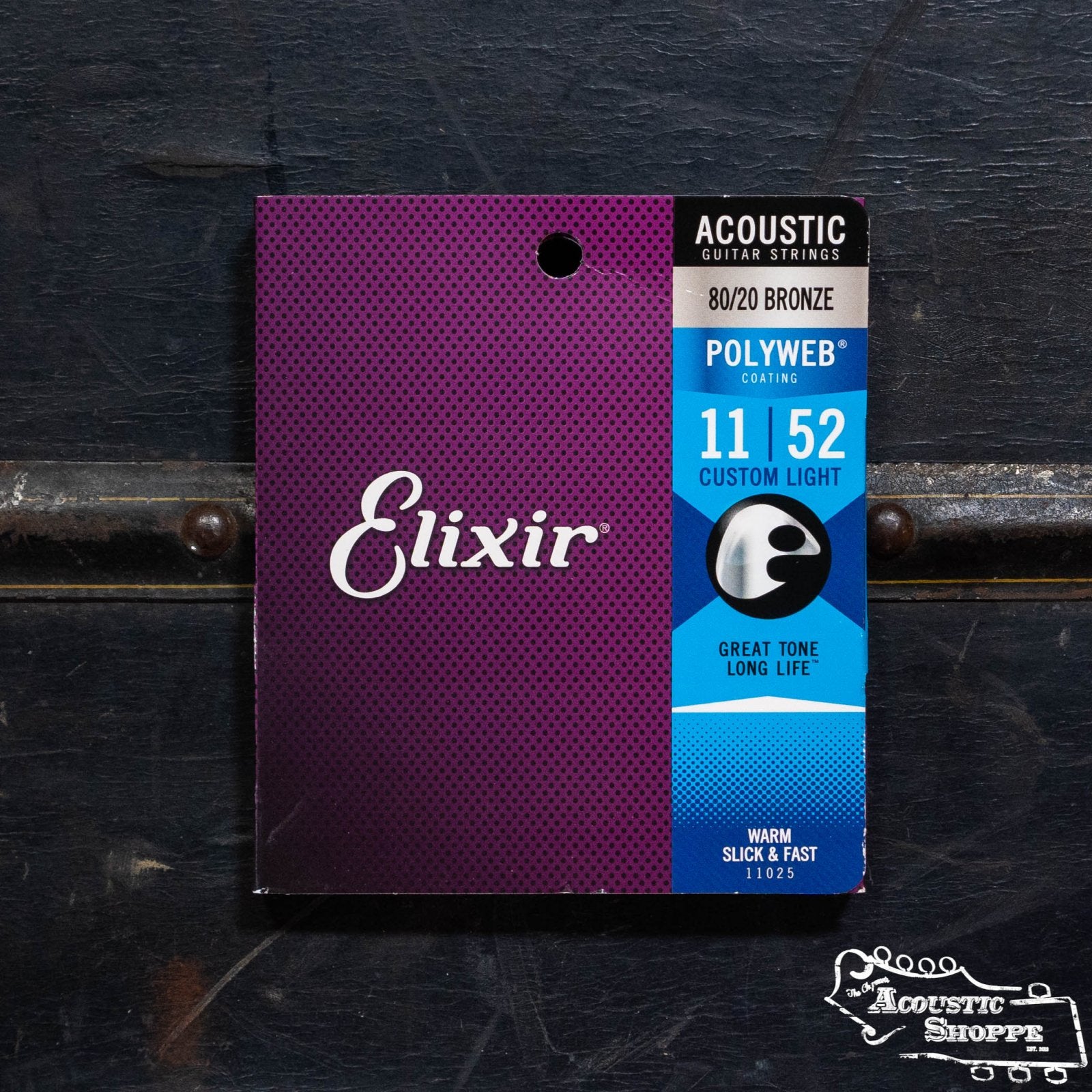 A package of Elixir 11025 Acoustic 80/20 Bronze with Polyweb Coating (11-52) guitar strings by Elixir is shown upright before a dark background, featuring The Acoustic Shoppe logo in the lower right—ideal for acoustic musicians.