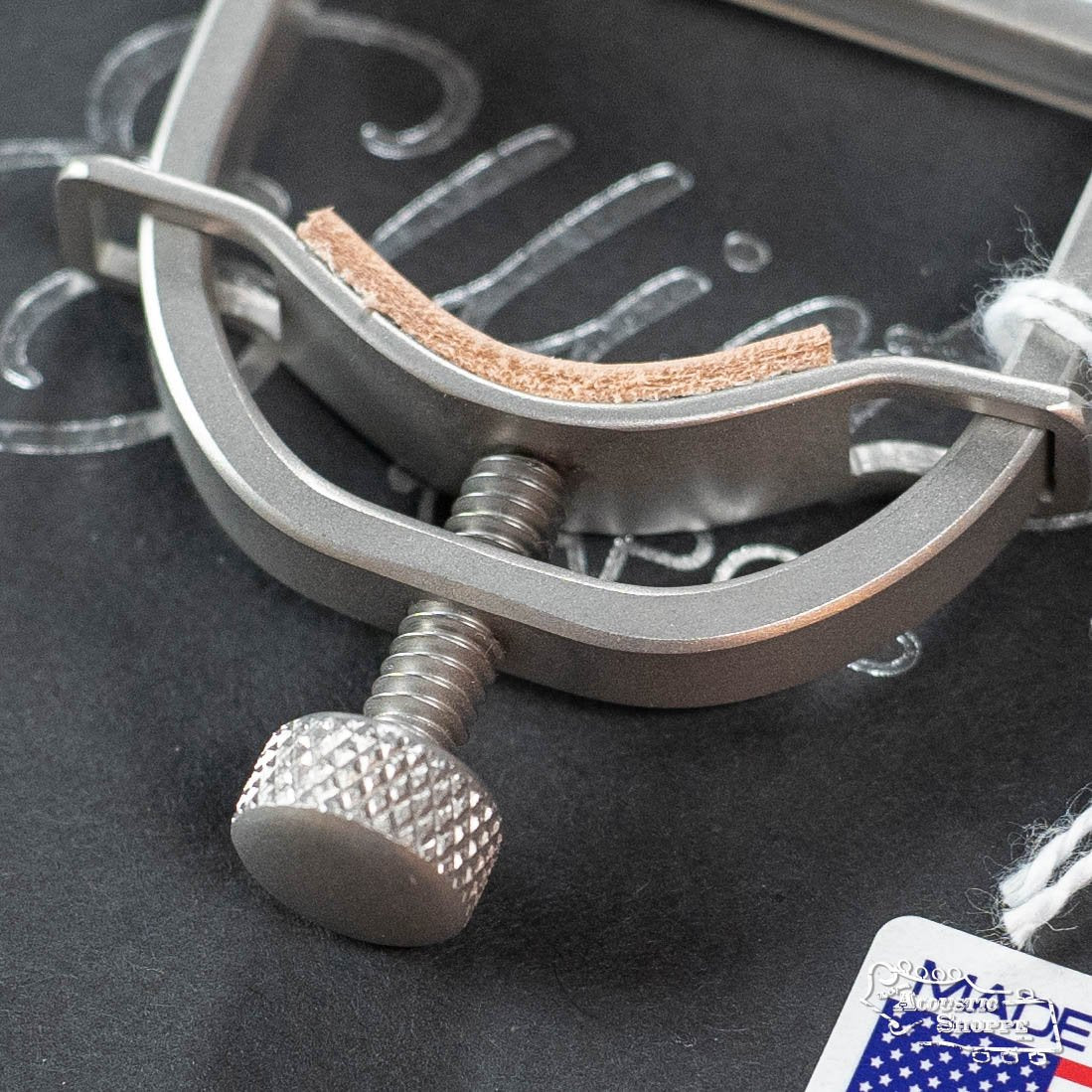 Close-up of the Elliott B450I Integrity Banjo Capo by Elliott Capos, featuring a textured tightening knob and leather padding—essential for banjo care. Available at your local Eastman dealer.