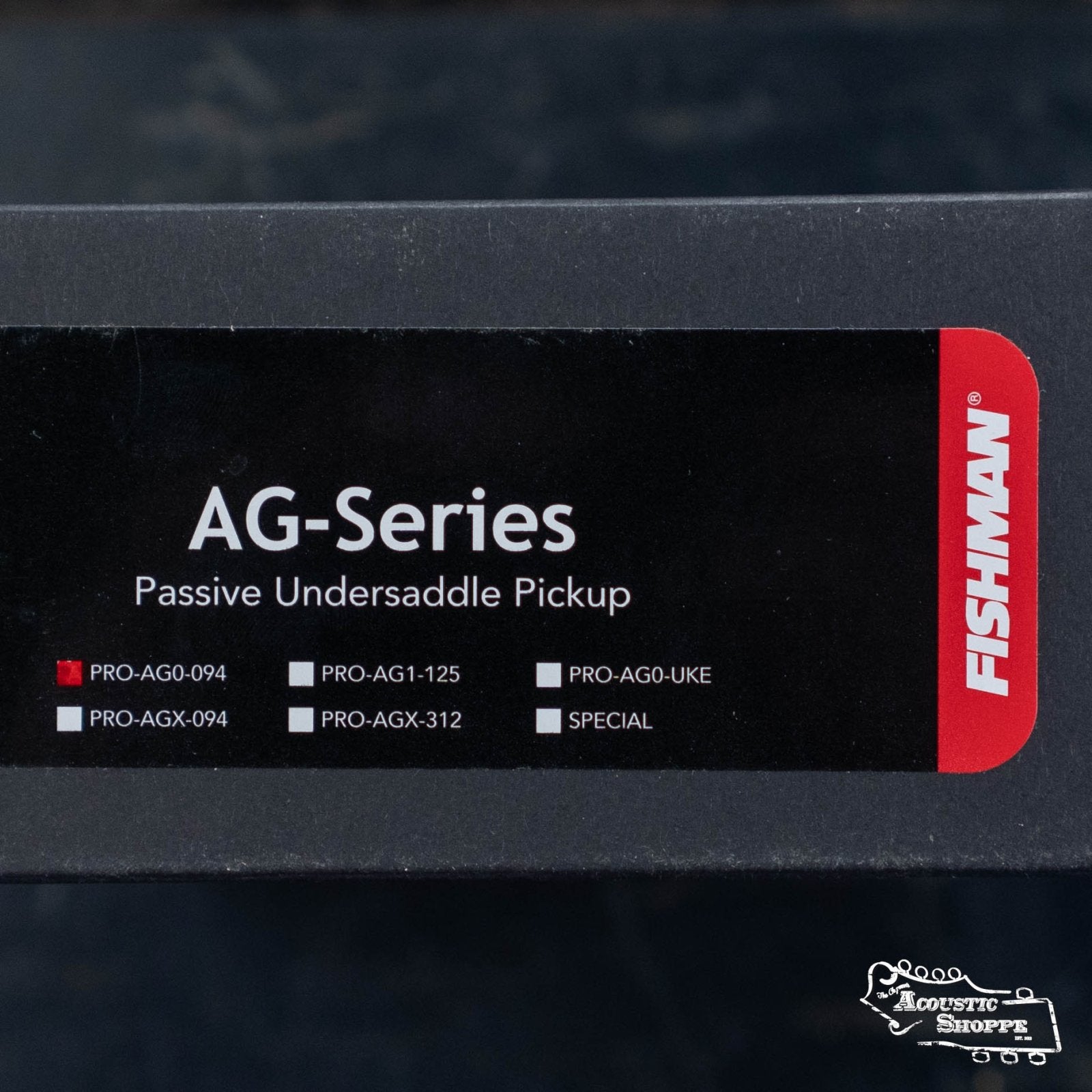 Close-up of the Fishman AG-Series Undersaddle Pickup for 6-string guitar (PRO-AG0-094) label, shown on a black background with red and white accents. The Acoustic Shoppe logo is visible in the bottom right corner.