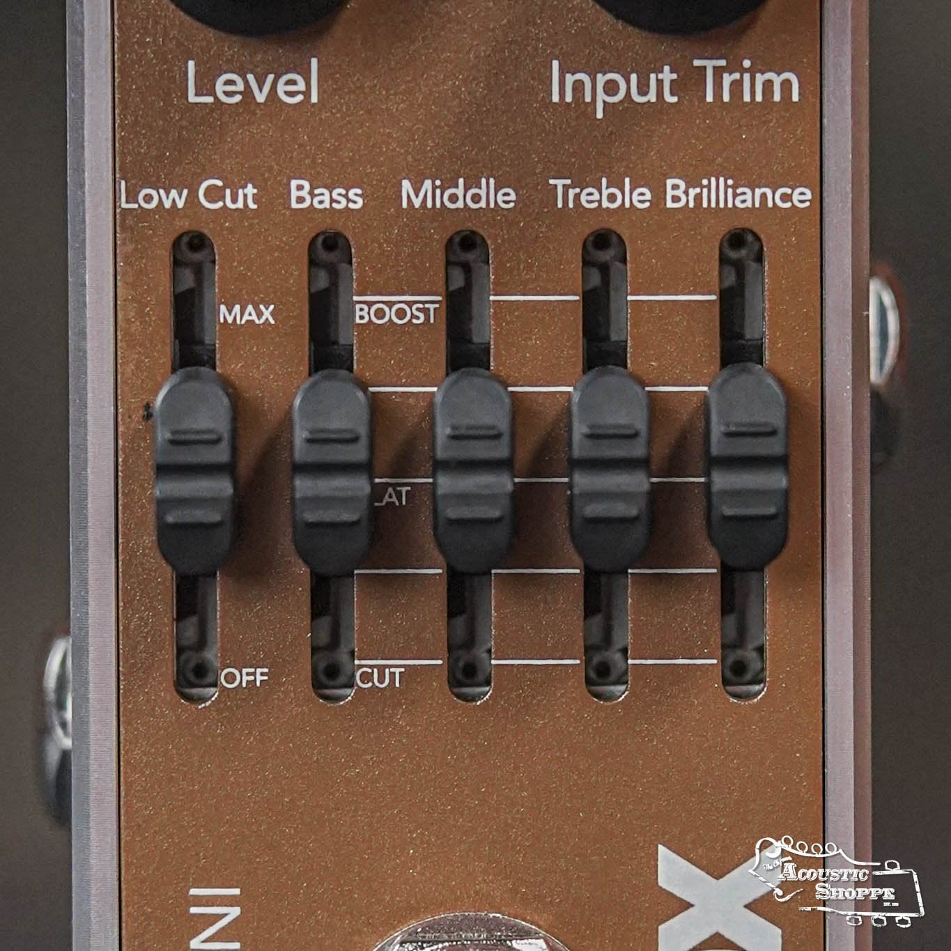 Close-up of the Fishman AFX Pro EQ Mini Acoustic Preamp & EQ PRO-AFX-EQ2, featuring five black sliders labeled Low Cut, Bass, Middle, Treble, and Brilliance on a brown background with white text—perfect as an acoustic preamp.