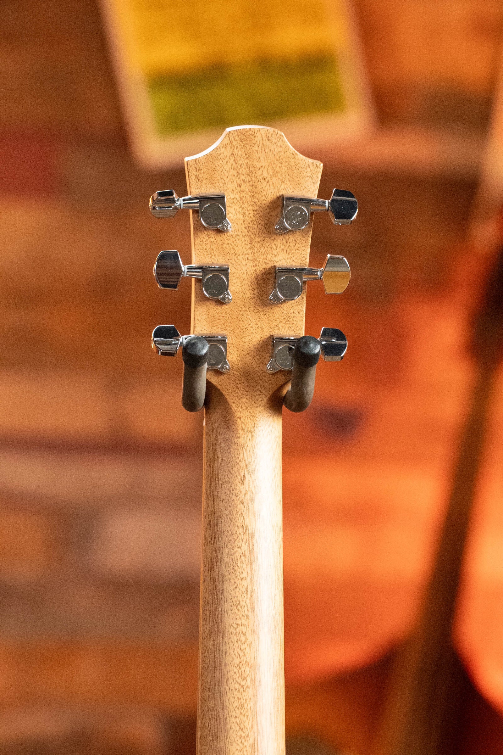 Close-up of the back of a Furch Masters Choice Green SB Dc-SR AA Sitka/AA Indian Rosewood Dreadnought Cutaway Sunburst Guitar w/LR Baggs Pickup #0020 headstock, displaying tuning pegs and wooden neck against a warm, blurred background.