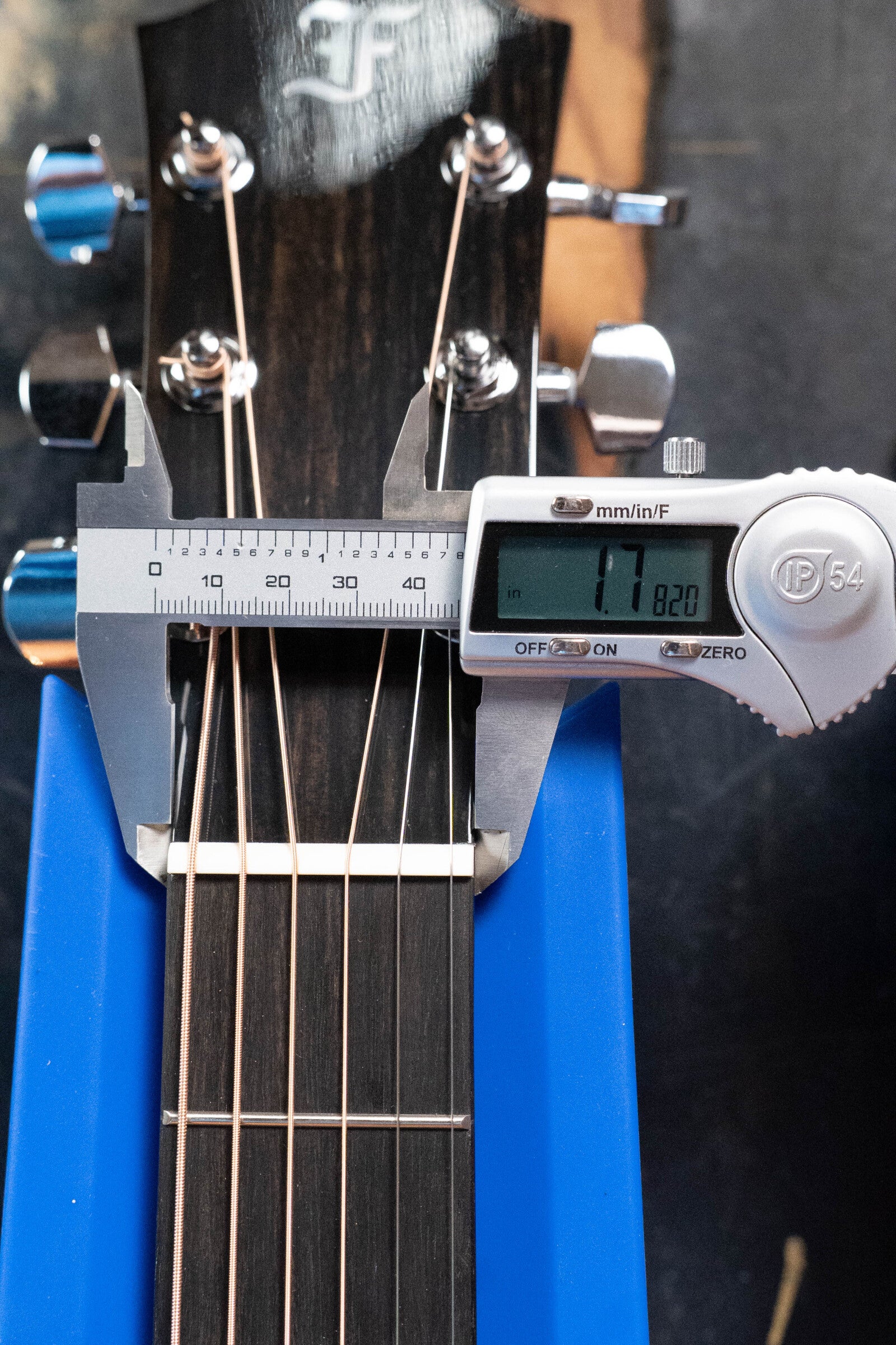 A digital caliper measures the nut width of a Furch Masters Choice Green SB Dc-SR AA Sitka/AA Indian Rosewood Dreadnought Cutaway Sunburst Guitar, displaying 42.0 mm, with its Sitka spruce top and headstock in view.
