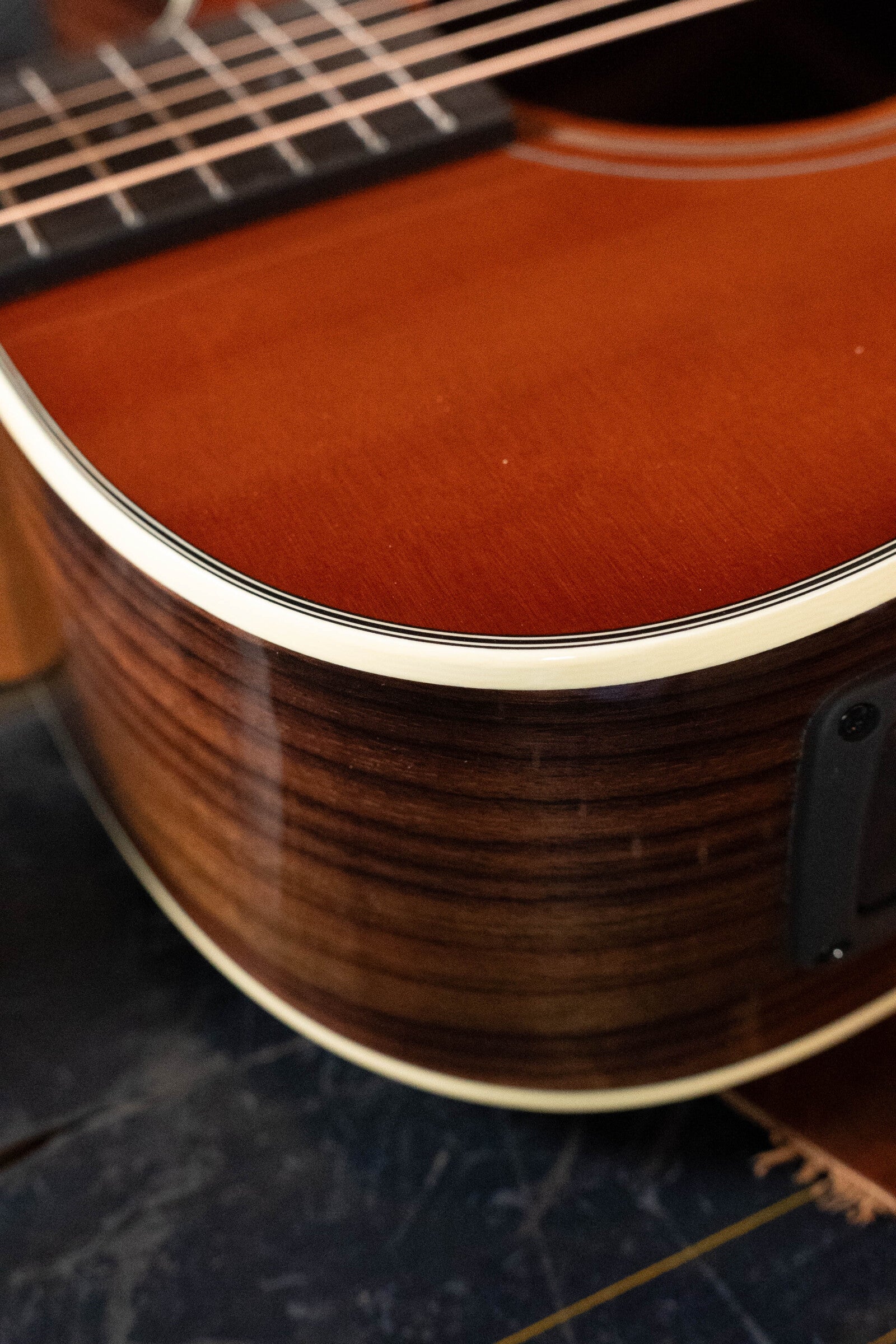 Close-up of the Furch Masters Choice Green SB Dc-SR AA Sitka/AA Indian Rosewood Dreadnought Cutaway Sunburst Guitar, showing its glossy finish, wood grain, light binding, and partial fretboard with sound hole.