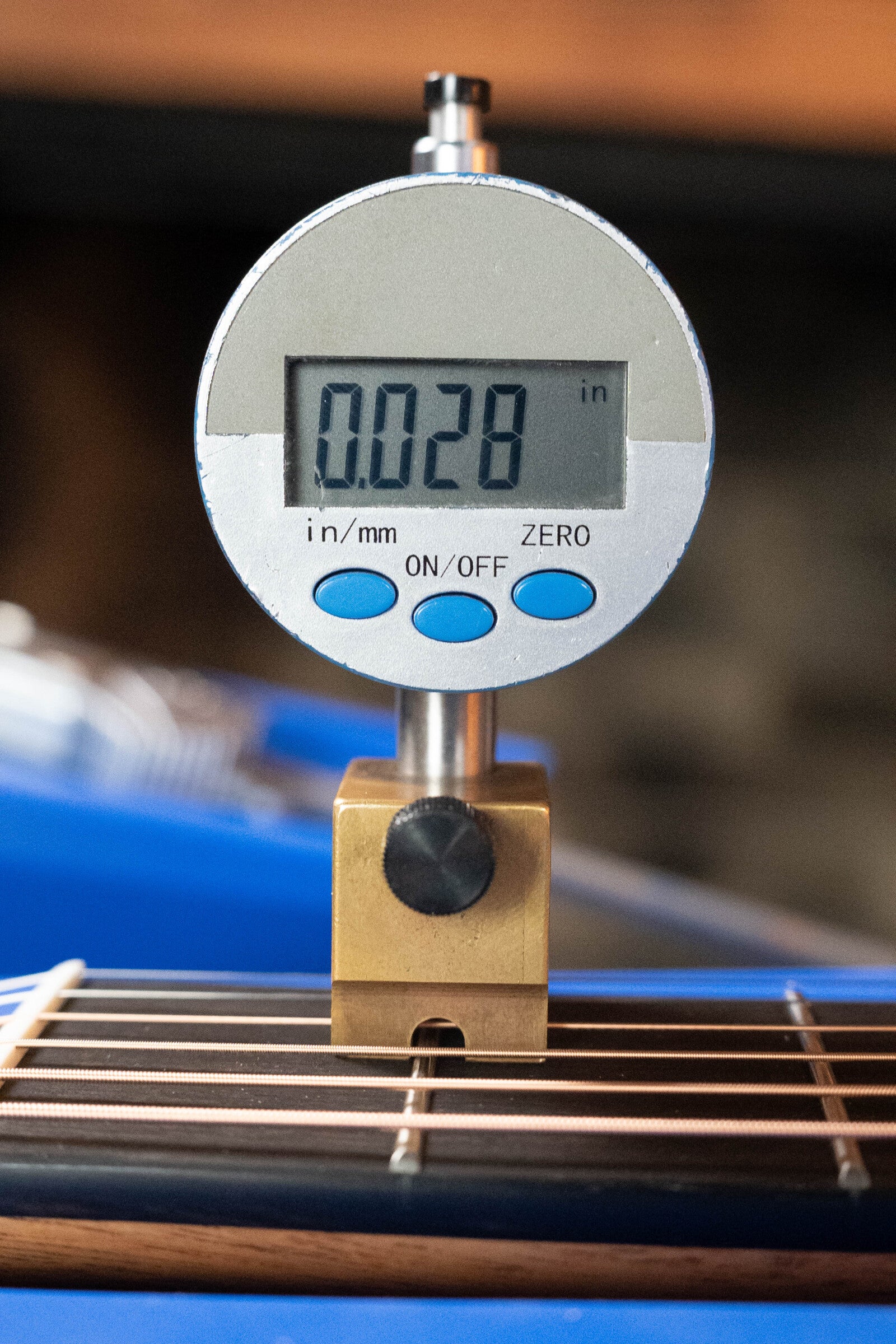 A digital gauge shows 0.028 inches above the strings of a Furch Masters Choice Green SB Dc-SR AA Sitka/AA Indian Rosewood Dreadnought Cutaway Sunburst Guitar, precisely measuring string height above the fretboard.