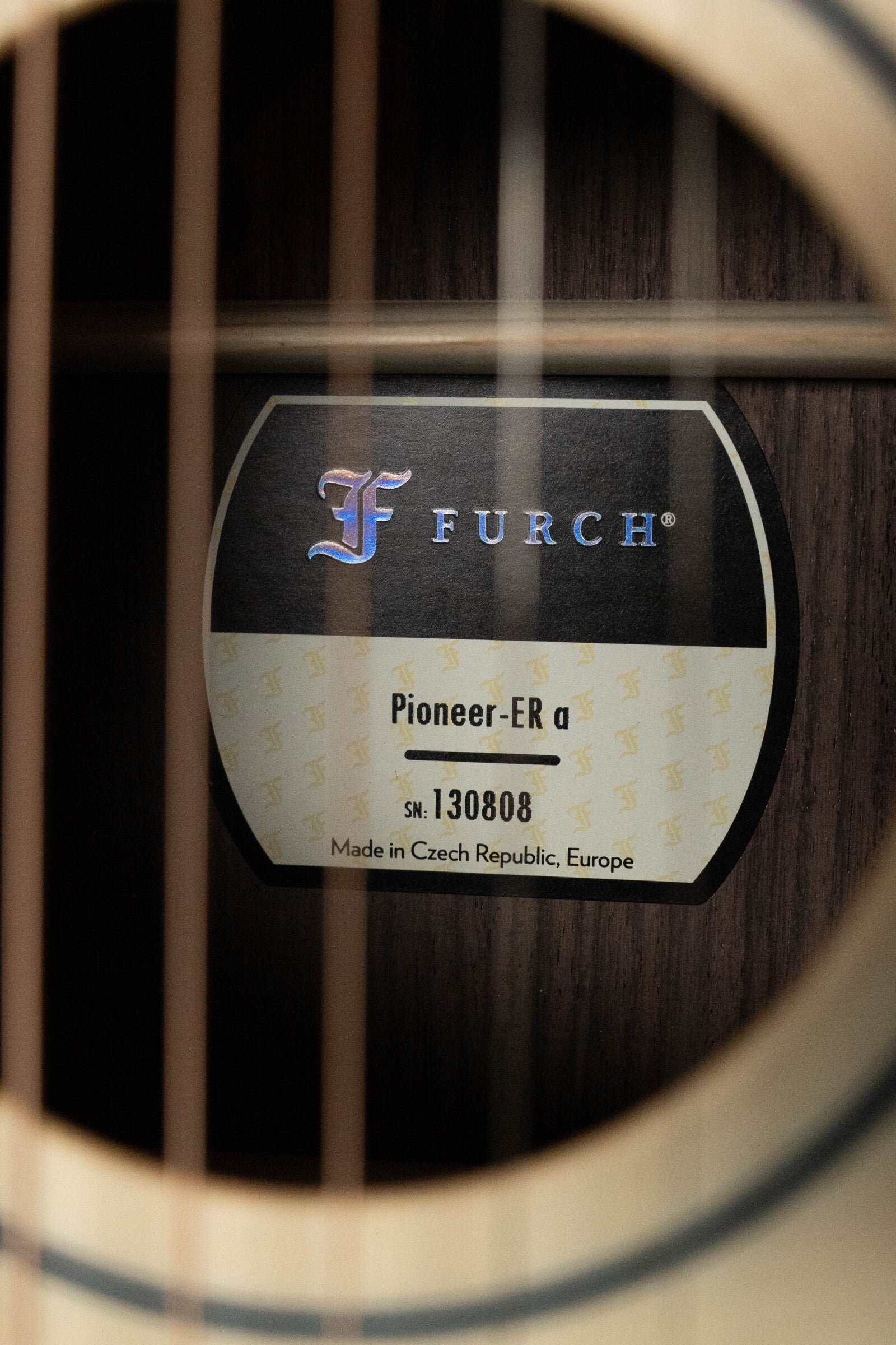 Close-up through guitar strings reveals the Furch label inside the soundhole of a Pioneer-ER VTC Engelmann Spruce/Indian Rosewood Cutaway Travel Guitar w/ Soundport Boosters & VTC Pickup, serial #0808, made in Czech Republic.