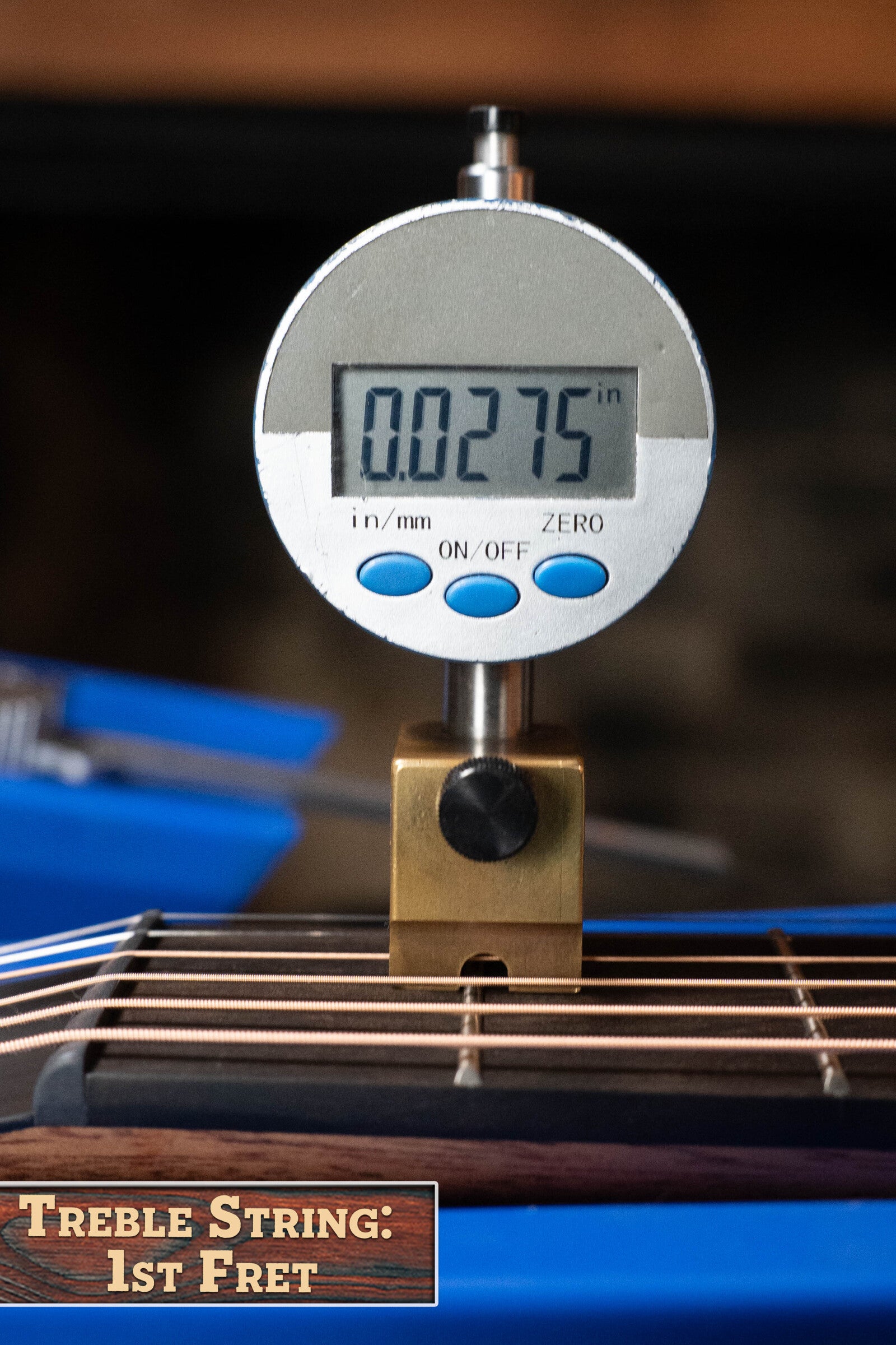 A digital gauge displays 0.0275 in while measuring the height of a Furch Pioneer-ER VTC Engelmann Spruce/Indian Rosewood Travel Guitar string at the 1st fret. The wooden label reads Treble String: 1st Fret in the lower left corner.