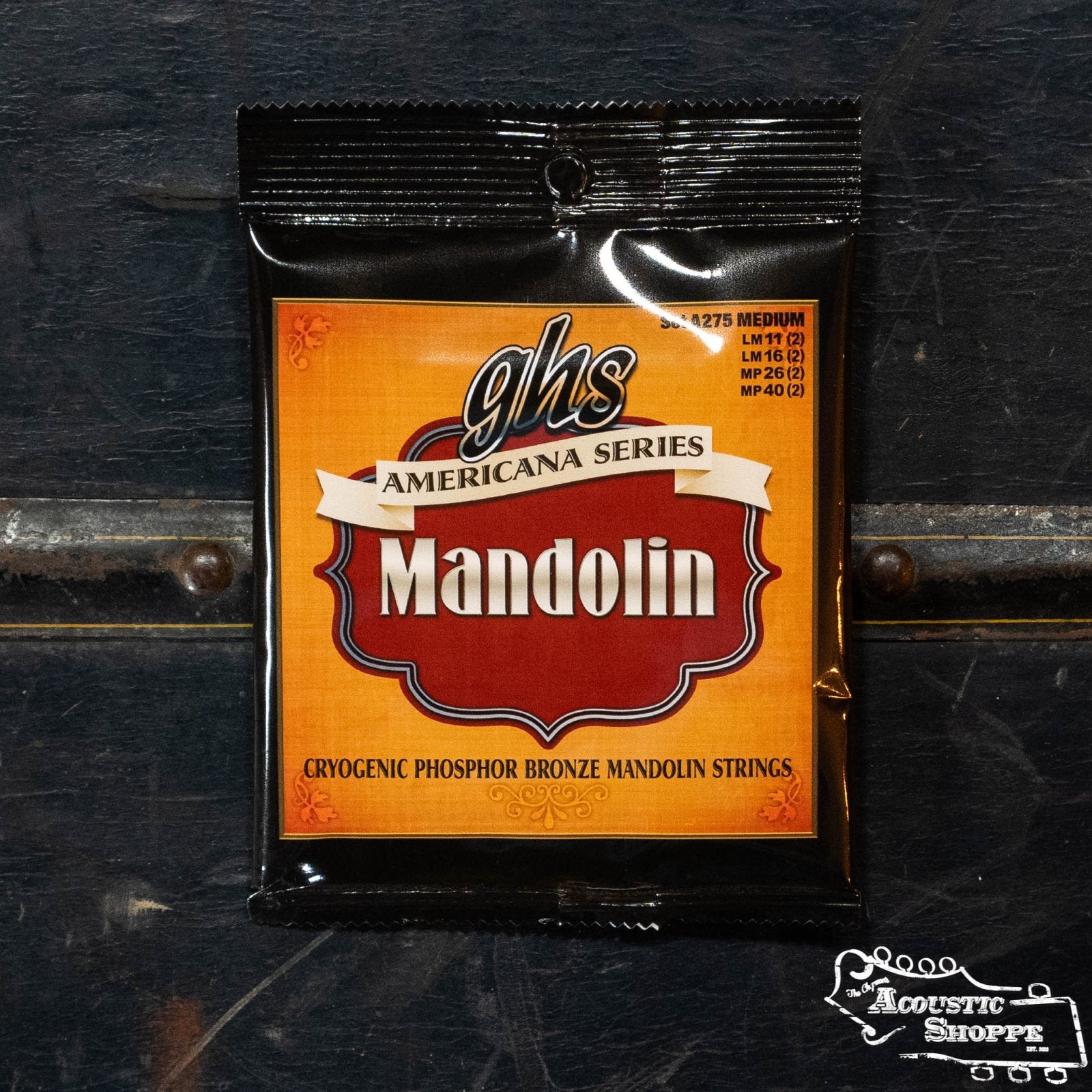 A package of GHS A275 Americana Series Phosphor Bronze Mandolin Strings - Medium by GHS Strings rests on a dark surface, featuring Mandolin on an orange and red label and The Acoustic Shoppe logo in the bottom right corner.