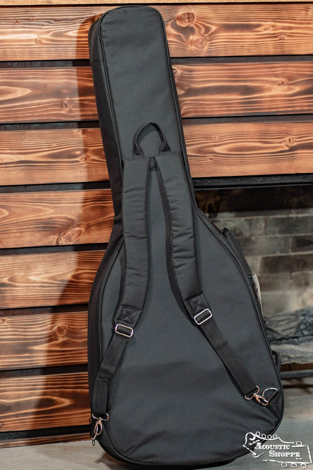 The Guild Guitars Deluxe Acoustic Gig Bag - Jumbo is a black, padded case with backpack straps, designed to protect your jumbo-size acoustic guitar. Perfect for musicians seeking style and security for their instrument.