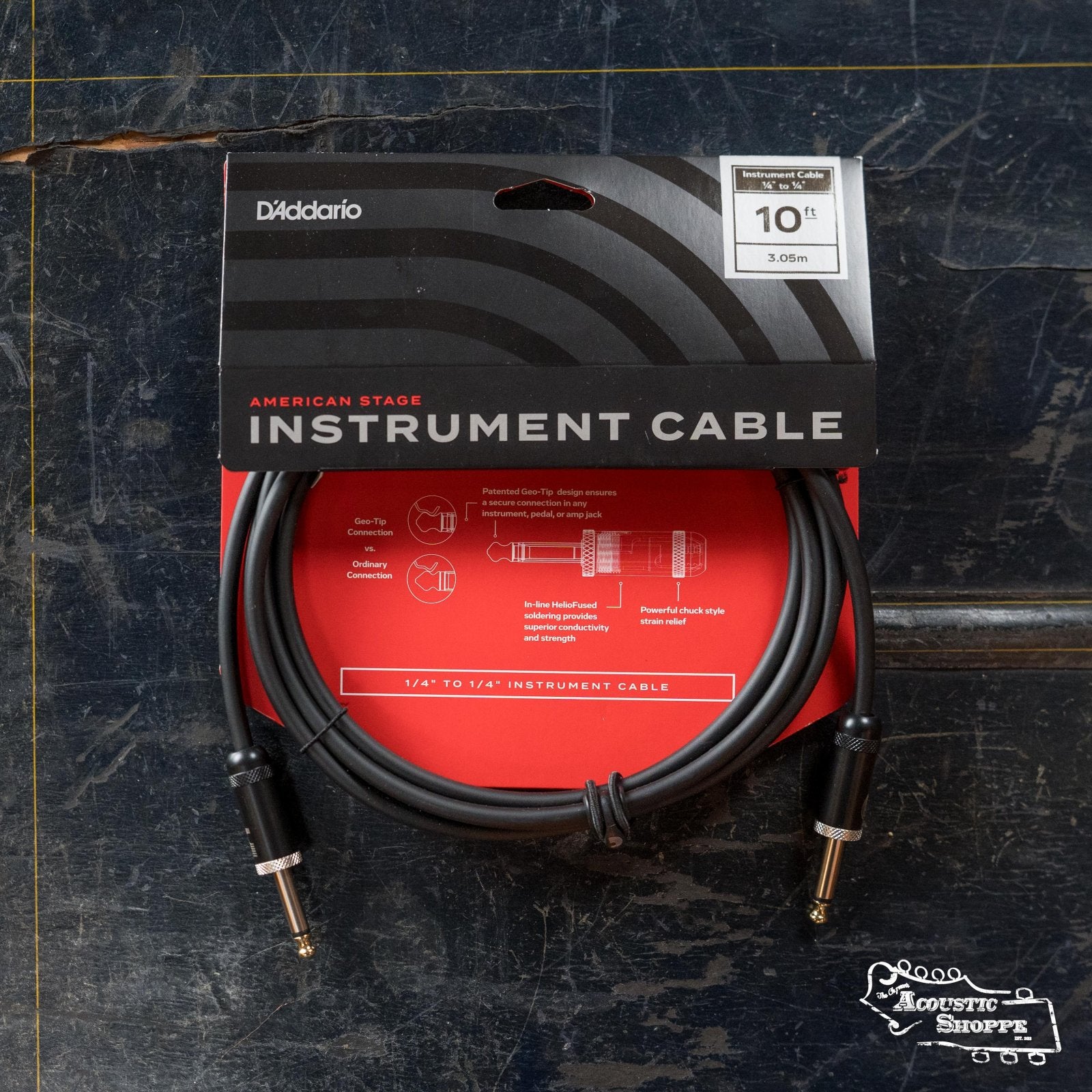 The D'Addario American Stage Instrument Cable PW-AMSG-10, 10 feet long, is shown coiled in black packaging with red and white text on a worn dark surface.