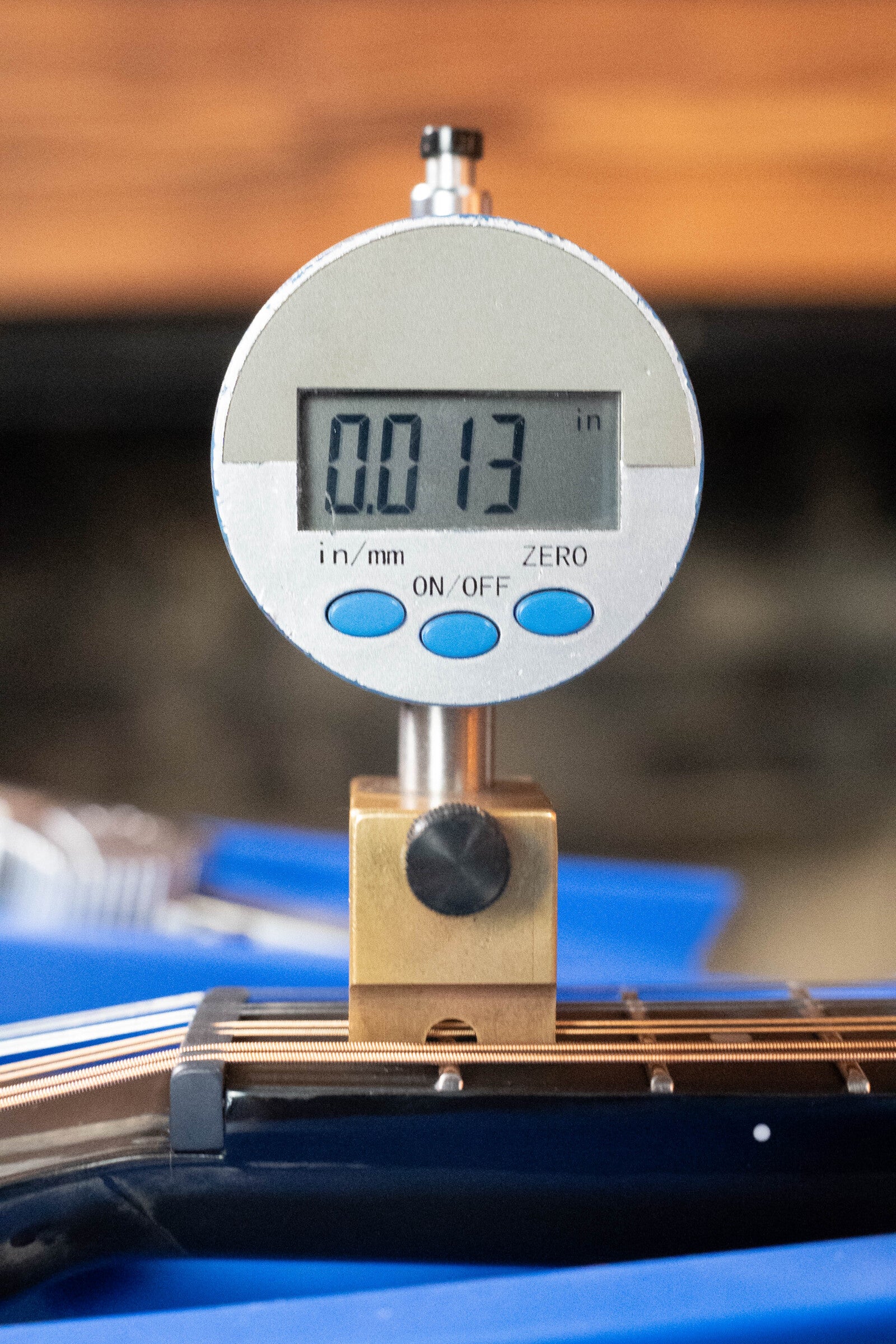 A digital gauge shows 0.013 inches when measuring the gap above the strings and fretboard of a KLOS CT_MA_DAE_EQ Full Carbon Unidirectional Black A-Style Mandolin w/KLOS EQ Pickup #4889 by KLOS Guitars.