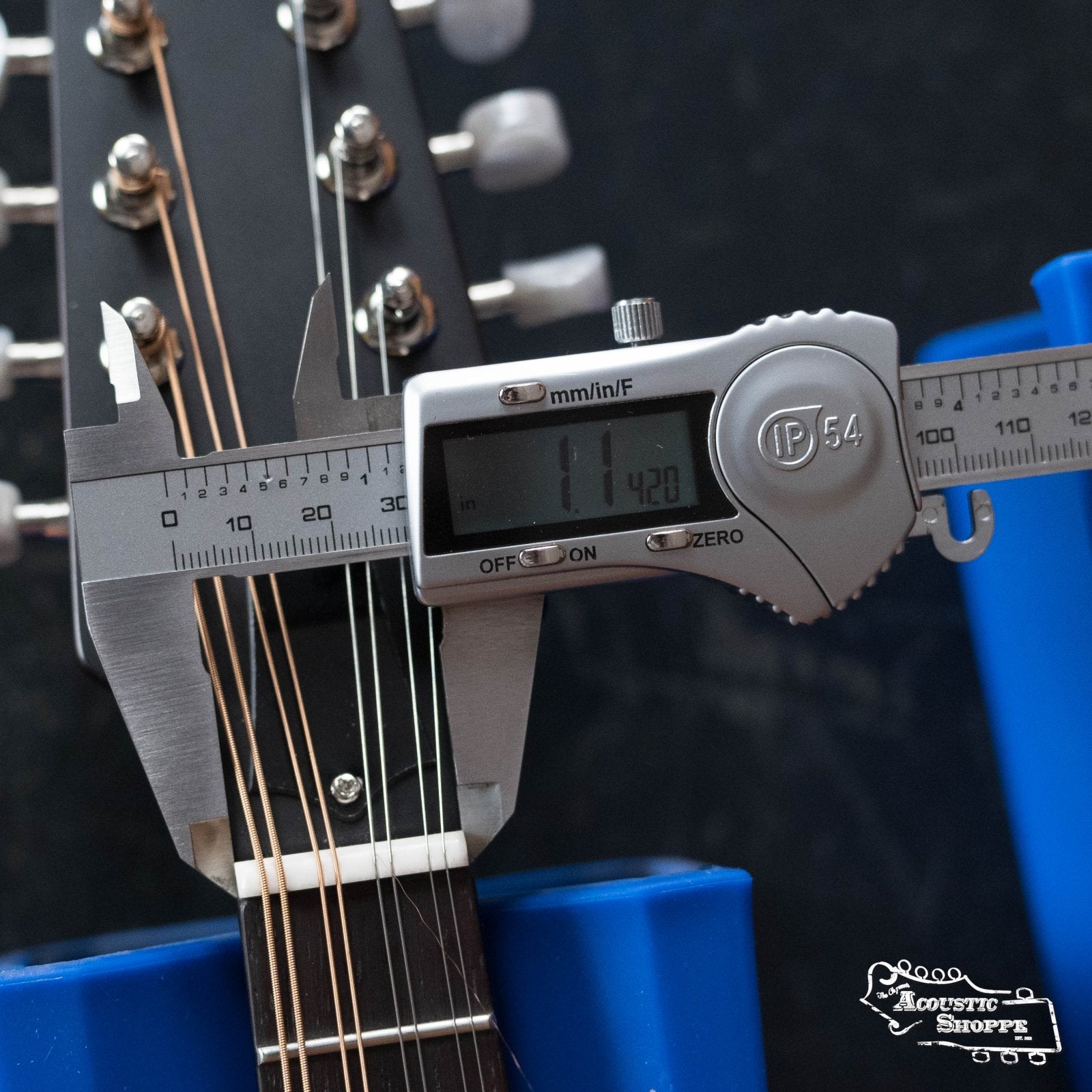 A digital caliper reads 1.1420 inches as it measures a guitar nut’s width. The same precision shapes The Loar LM-110E-BRB "Honey Creek" A-Style Brownburst Mandolin w/Pickup #0688, which features a solid spruce top.