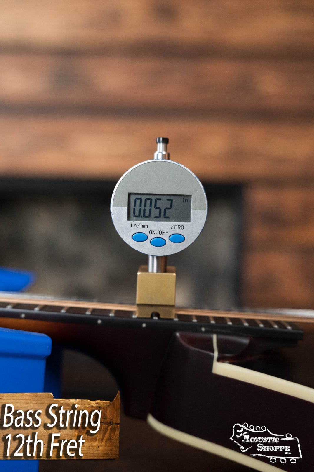A digital gauge measures the height of a bass string at the 12th fret of The Loar LM-110E-BRB "Honey Creek" A-Style Mandolin; the display reads 0.052 inches. “Bass String 12th Fret” appears bottom left with The Loar logo bottom right.