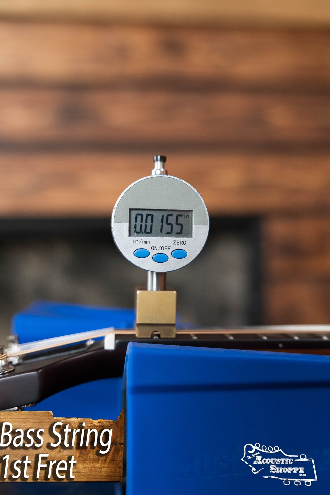 A digital gauge reads 0.155 inches while measuring the bass string height at the 1st fret of The Loar LM-110E-BRB "Honey Creek" A-Style Brownburst Mandolin w/Pickup, with 'Bass String 1st Fret' text overlaid on the image.