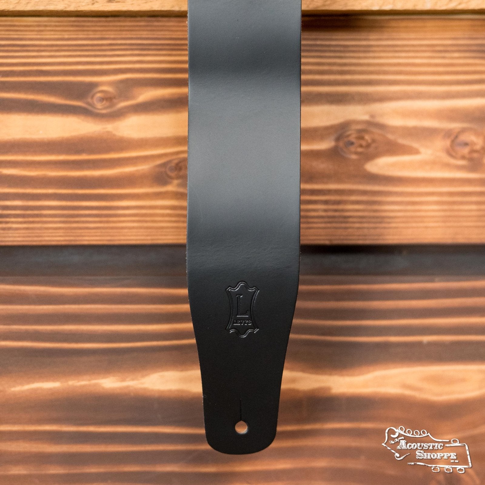 Black genuine leather guitar strap with embossed logo and adjustable hole on wooden background. - Levy's Genuine Leather Guitar Strap M26-BLK - Default Title
