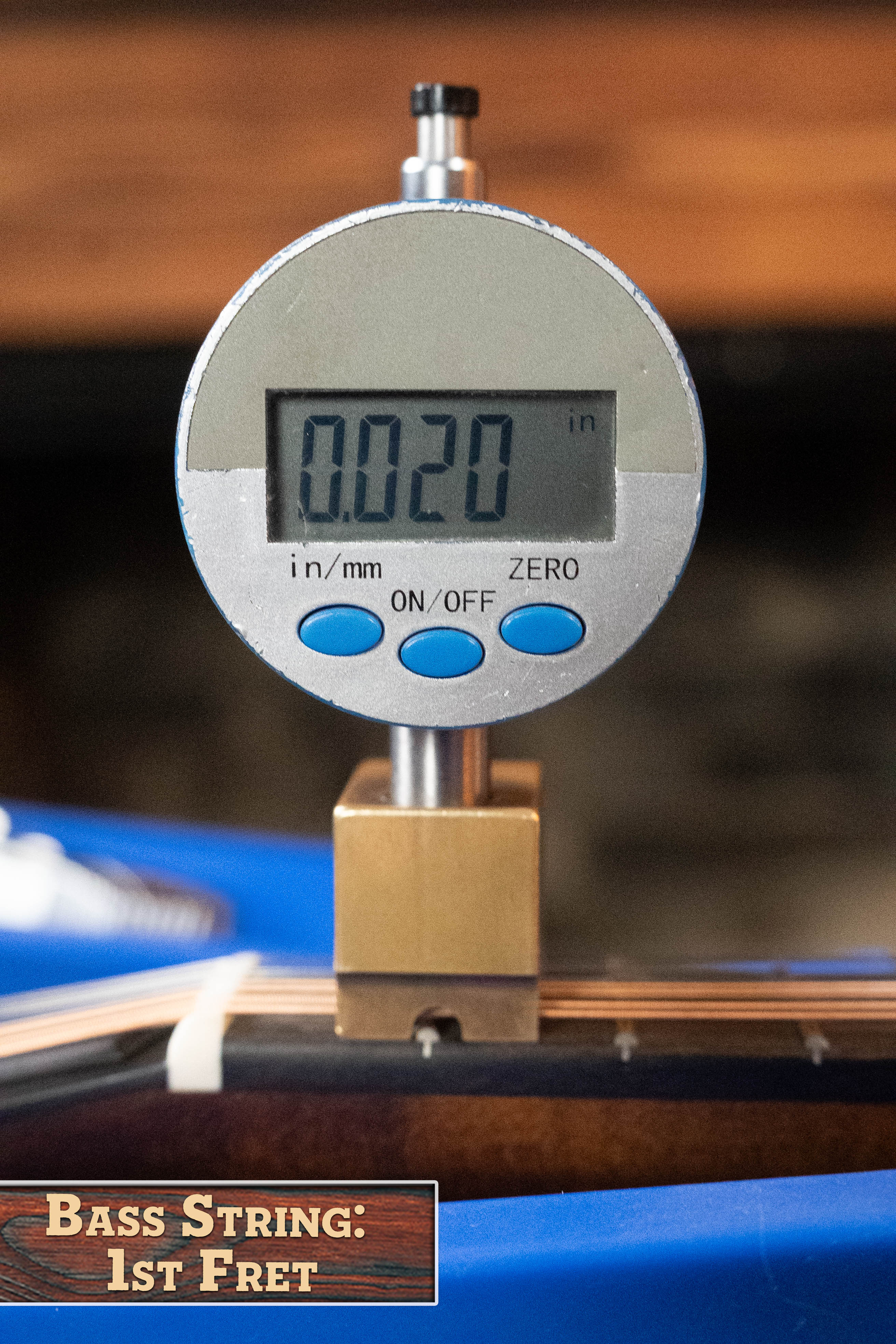 A digital caliper displays 0.020 inches while measuring the bass string height above the 1st fret of an Eastman MD305 Spruce/Maple A-Style Hand-Carved Mandolin (#3596) by Eastman Guitars. Label: Bass String, 1st Fret.