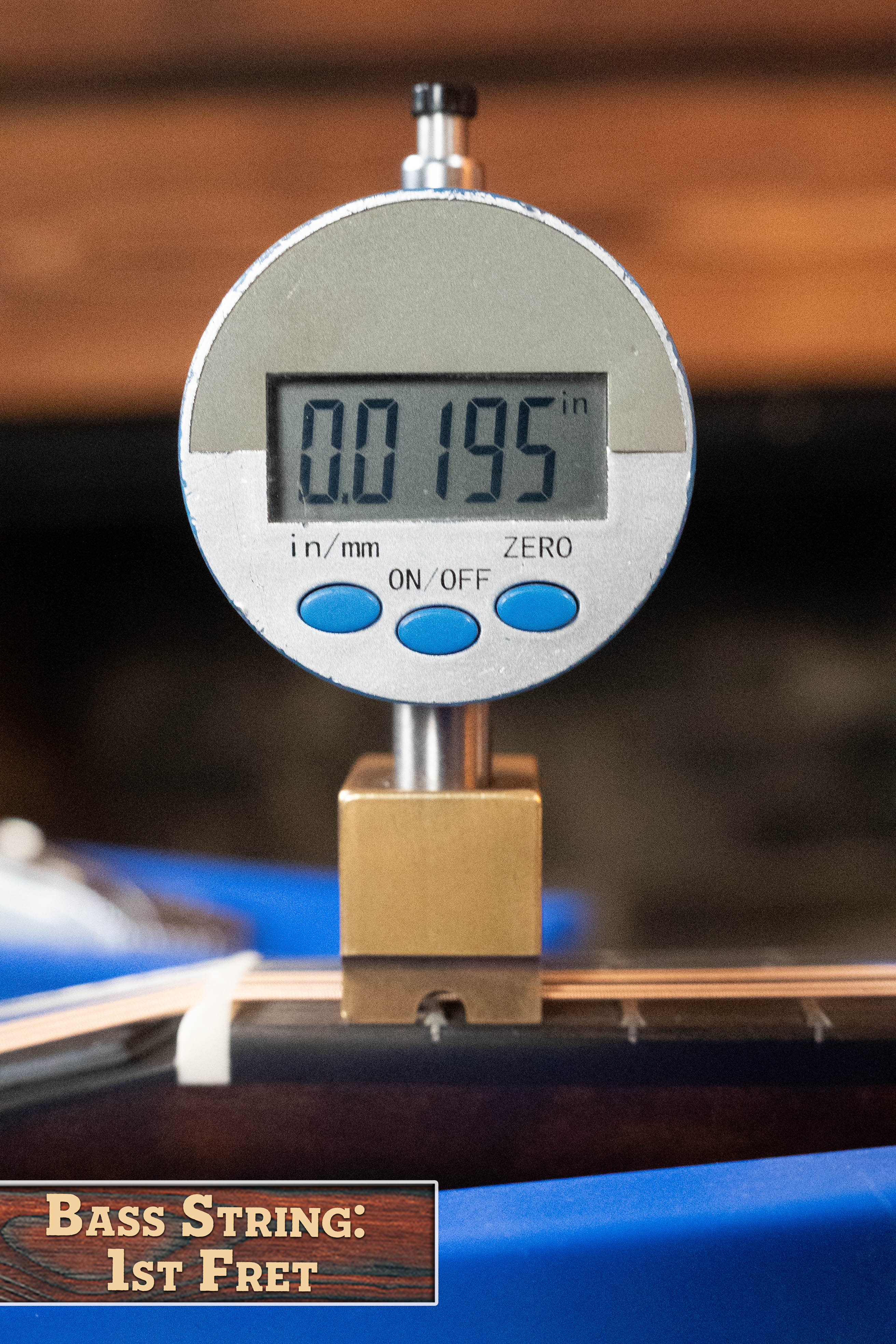 A digital gauge shows 0.0195 in while measuring a bass guitar string’s height at the first fret, similar to the precise setup on the Eastman Guitars MD315 F-Style Hand-Carved Mandolin #0917. A label reads: Bass String: 1st Fret.