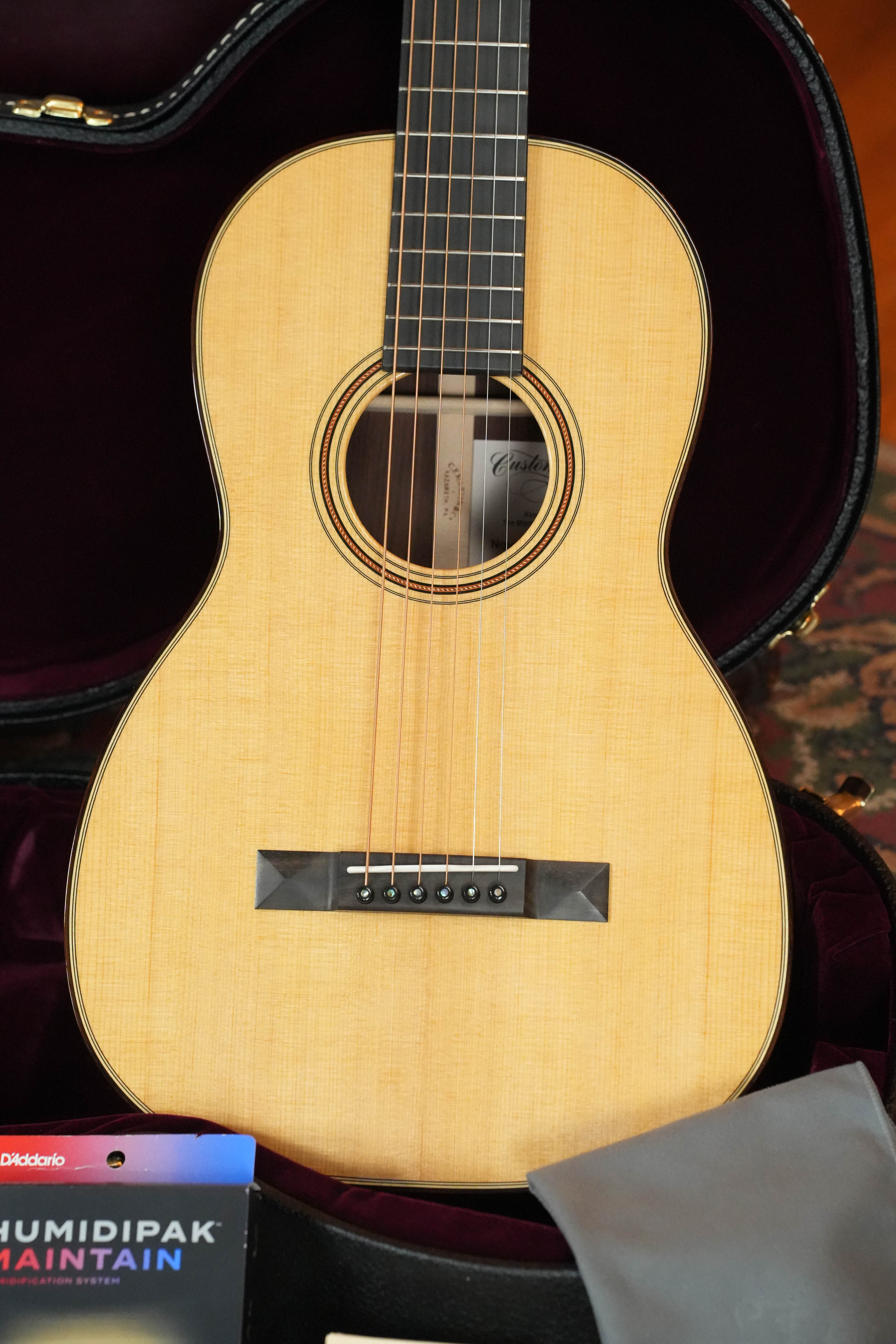 The Martin & Co. Custom Shop Sitka/Rosewood Acoustic Guitar #6904, with a VTS Sitka spruce top and light wood body, is displayed in an open hard case; DAddario Humidipak Maintain packaging and a gray cloth are nearby.