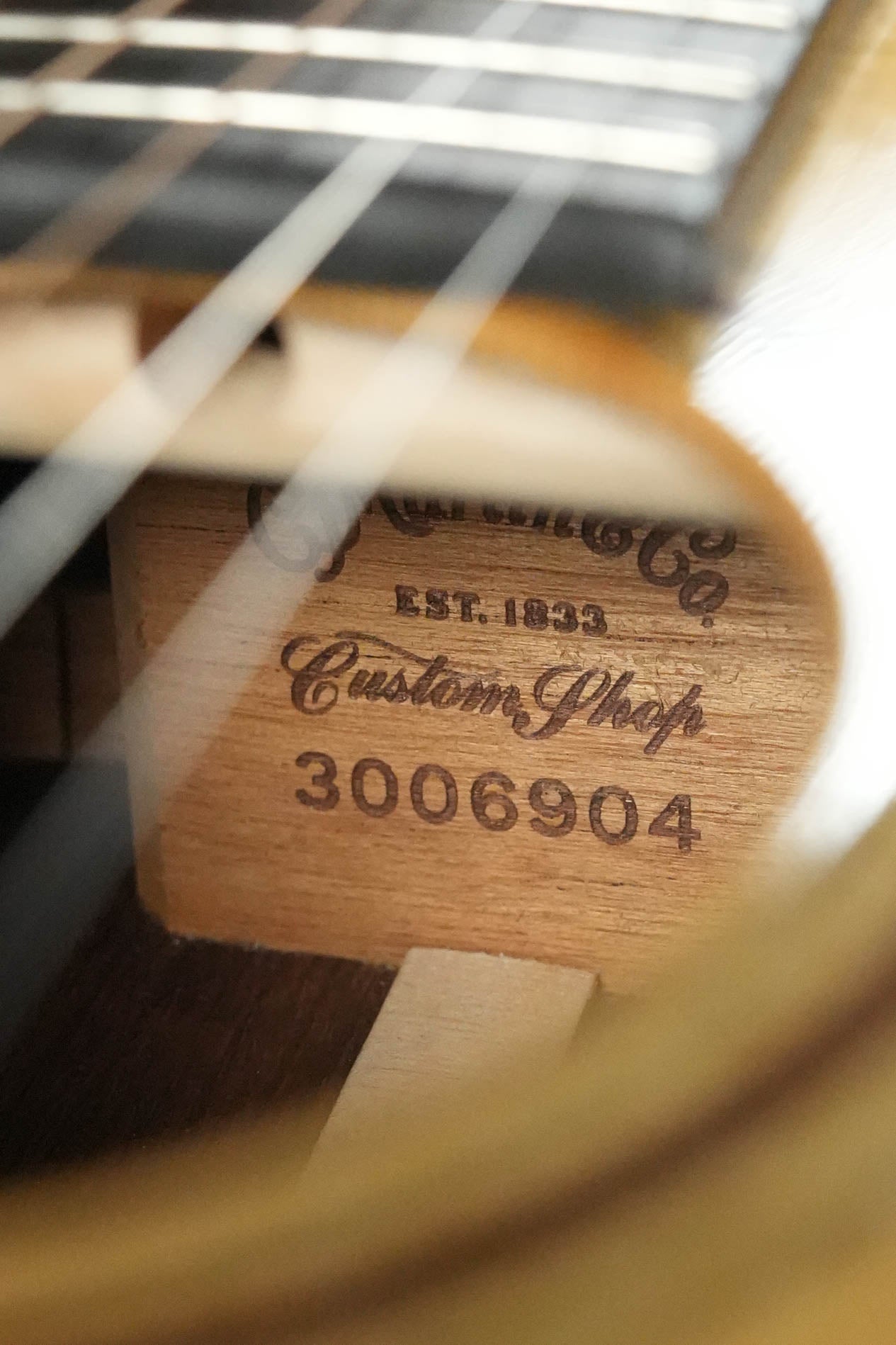Close-up of a Martin & Co. Custom Shop Sitka/Rosewood Acoustic Guitar #6904 interior, showing a wood label with "Est. 1833 Custom Shop 3006904" beneath the strings and sound hole.