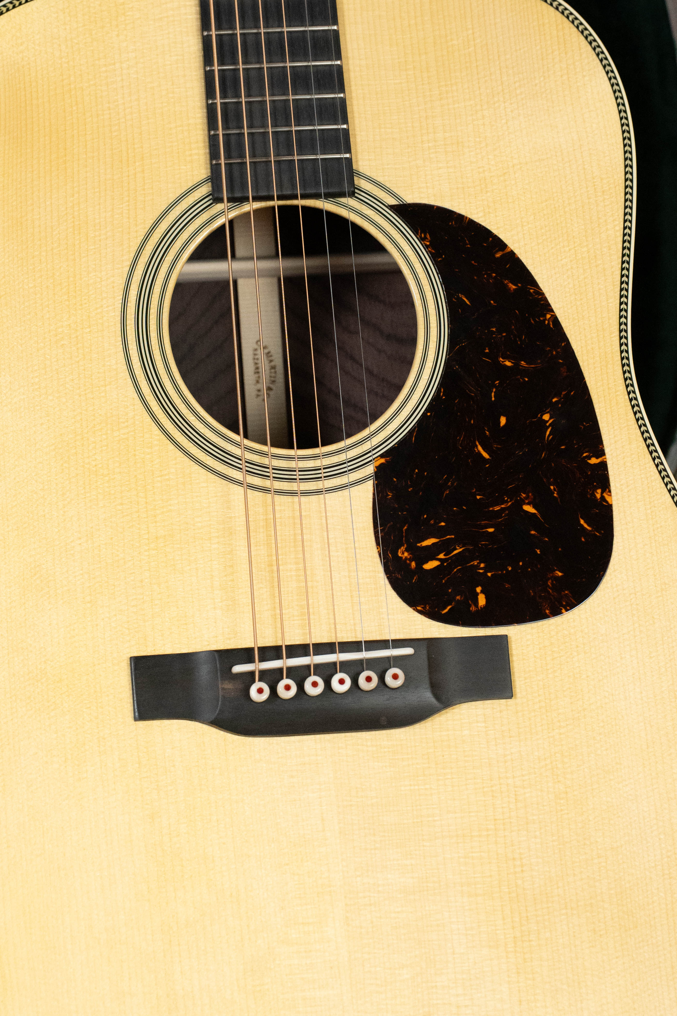 Close-up of a Martin & Co. Custom Shop HD-28 Style Spruce/Wild Grain Rosewood Dreadnought Acoustic Guitar #7410, highlighting the soundhole, strings, marbled pickguard, and fretboard set against a light Adirondack spruce top.