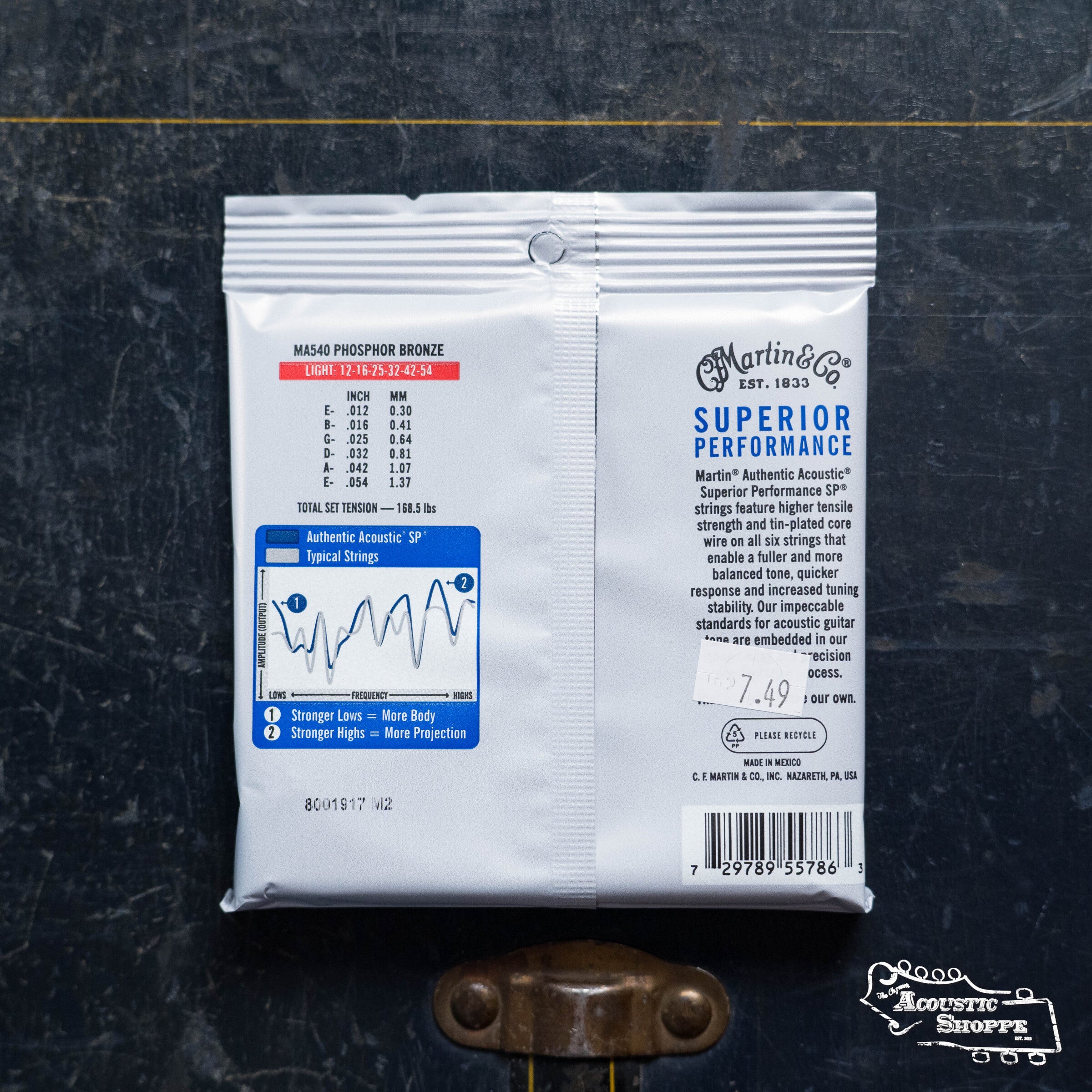 A pack of Martin & Co. Authentic Light Acoustic SP Guitar Strings - Silk & Steel 41Y18MA540 lies on a dark surface, showing specs, tuning stability info, a performance chart, branding details, and a $7.49 price tag on the back.
