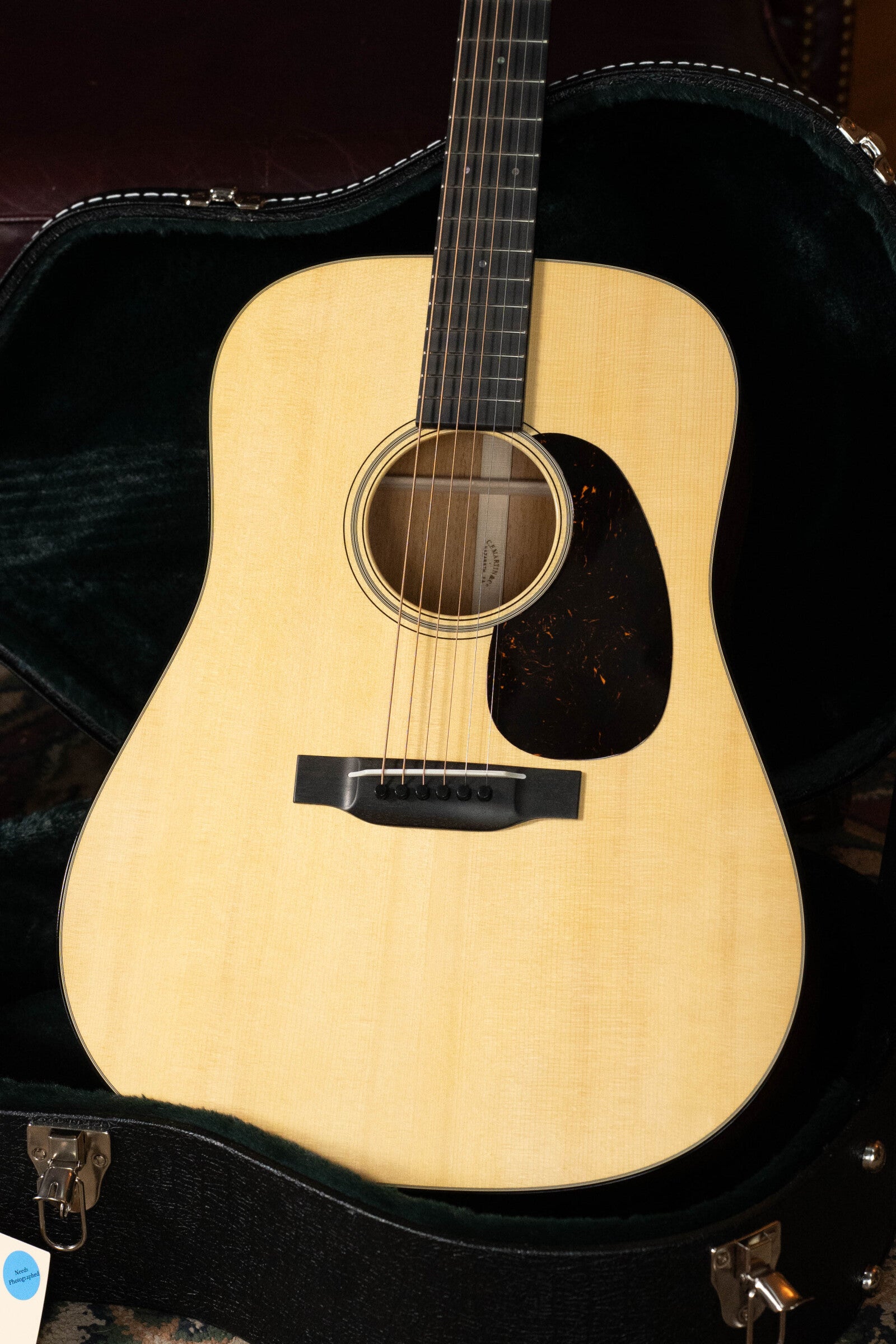 A Martin & Co. Custom Shop D-18V Adirondack/Mahogany Dreadnought Acoustic Guitar #6905 with a dark pickguard sits in an open black hard case lined with green velvet, showcasing its natural wood finish and visible strings.