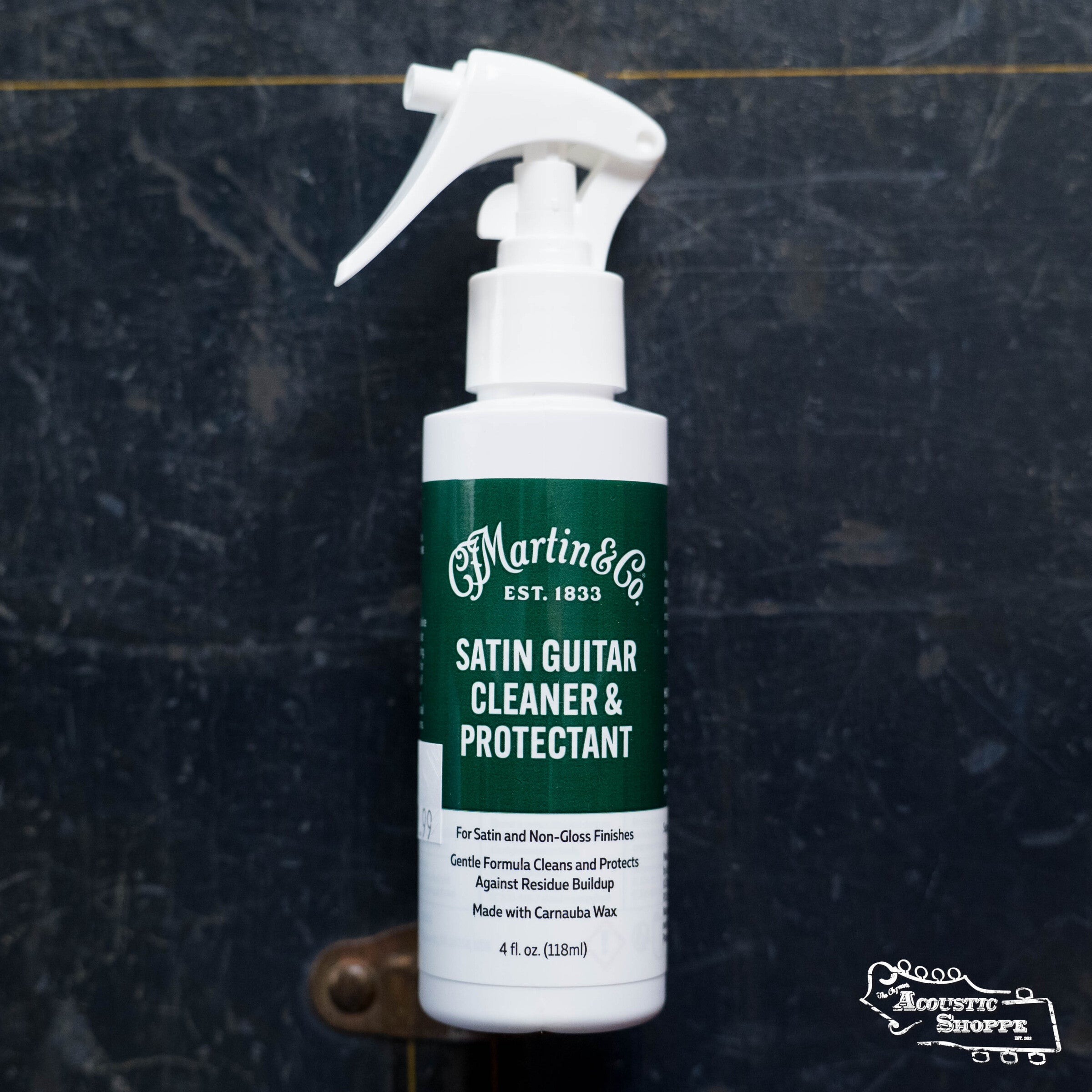 A bottle of Martin Guitar Satin Cleaner & Protectant by Martin & Co. for satin and non-gloss finishes rests on a dark background, with The Acoustic Shoppe logo in the lower right, highlighting this trusted guitar care product.