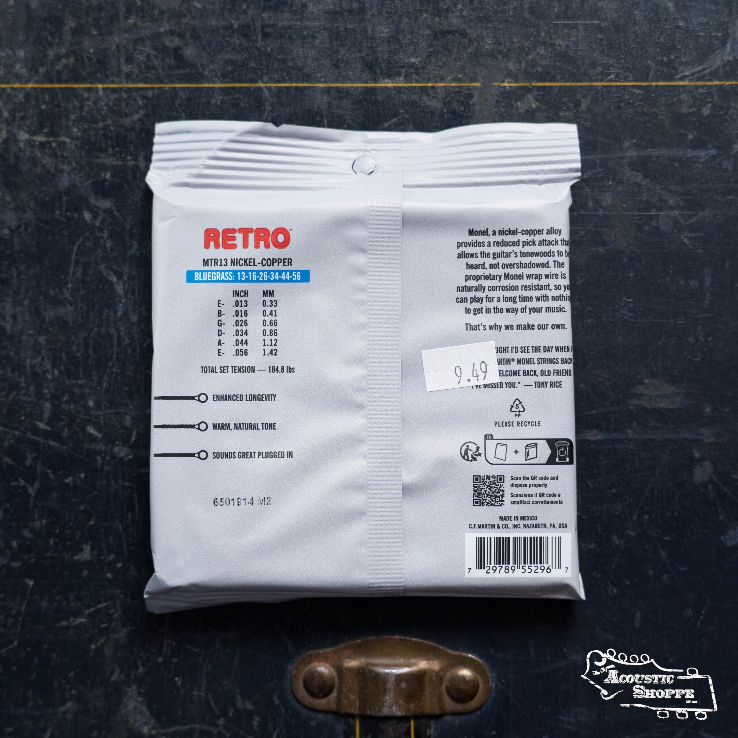 A package of Martin & Co. Retro Bluegrass-Tony Rice's Choice Acoustic Guitar Strings (41Y19MM13) sits on a dark surface, displaying the back label with details, gauges, barcodes, a $9.99 price tag, and The Acoustic Shoppe logo in the corner.