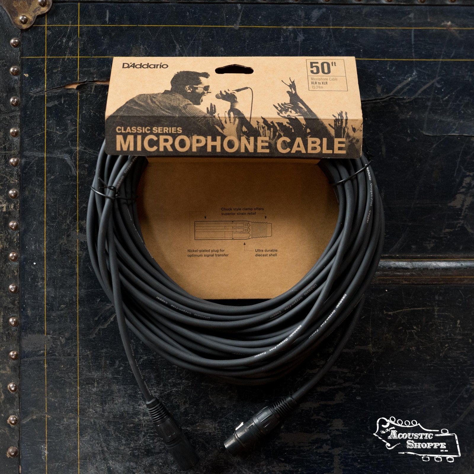 A D'Addario Classic Series XLR Microphone Cable 50 feet (PW-CMIC-50) by D’Addario is shown coiled and packaged, with black connectors, on a dark, grid-lined surface—engineered for excellent noise rejection.