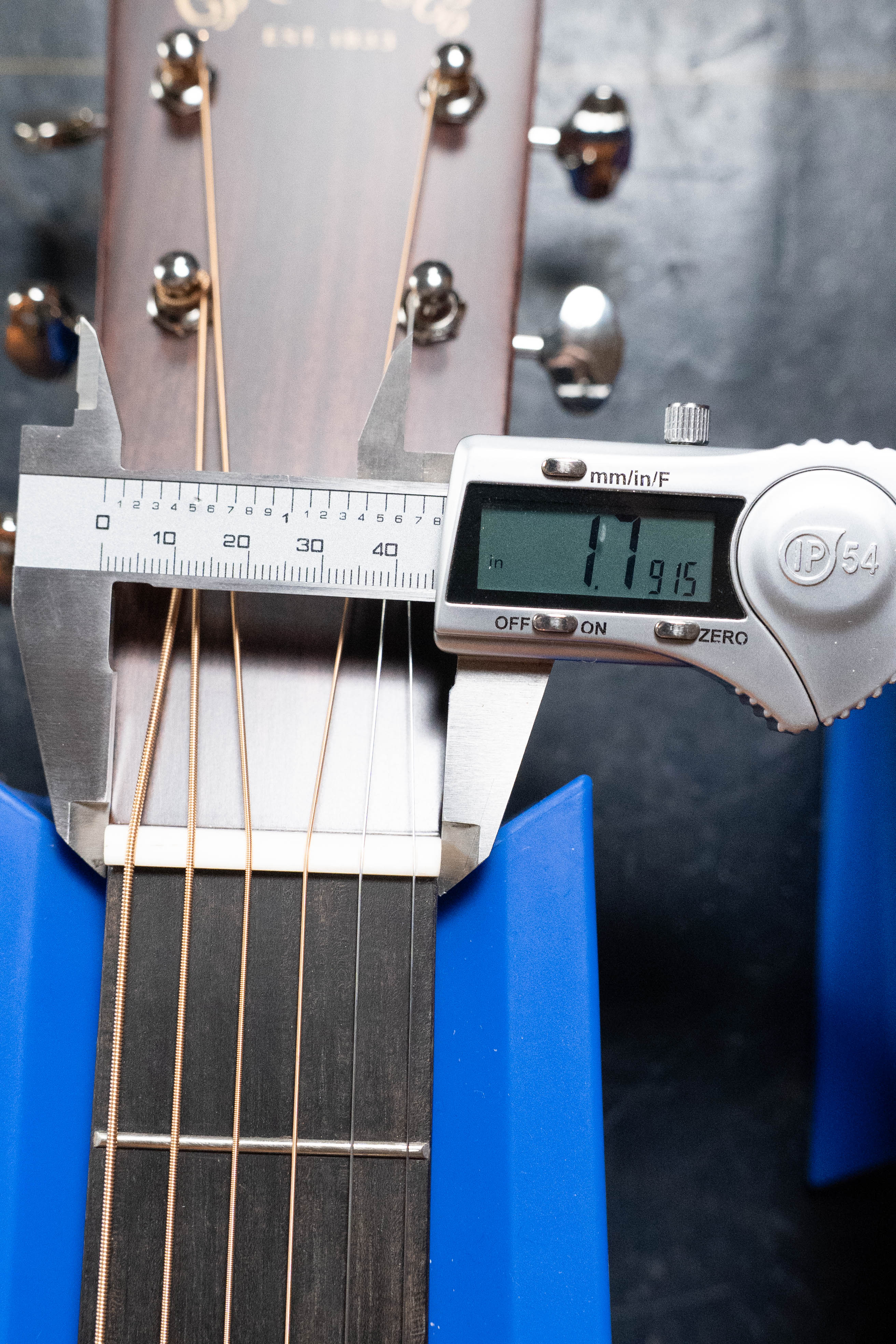 A digital caliper measures the nut width of a *New 2025 Model* Martin & Co. D-18 1933 Gloss Ambertone Spruce/Mahogany Dreadnought #6784, displaying 1.7915 inches as the guitar rests securely on blue supports.