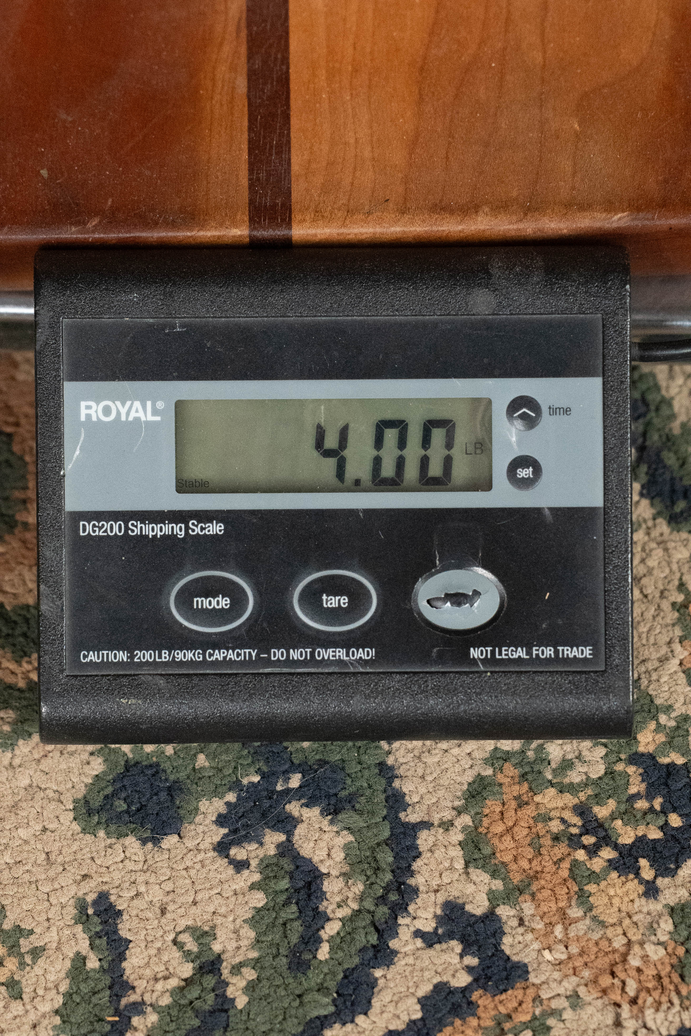 A digital shipping scale reads 4.00 lbs on a patterned carpet, with part of a Martin & Co. *New 2025 Model* D-18 1933 Gloss Ambertone Spruce/Mahogany Dreadnought Acoustic Guitar #6784 visible above.