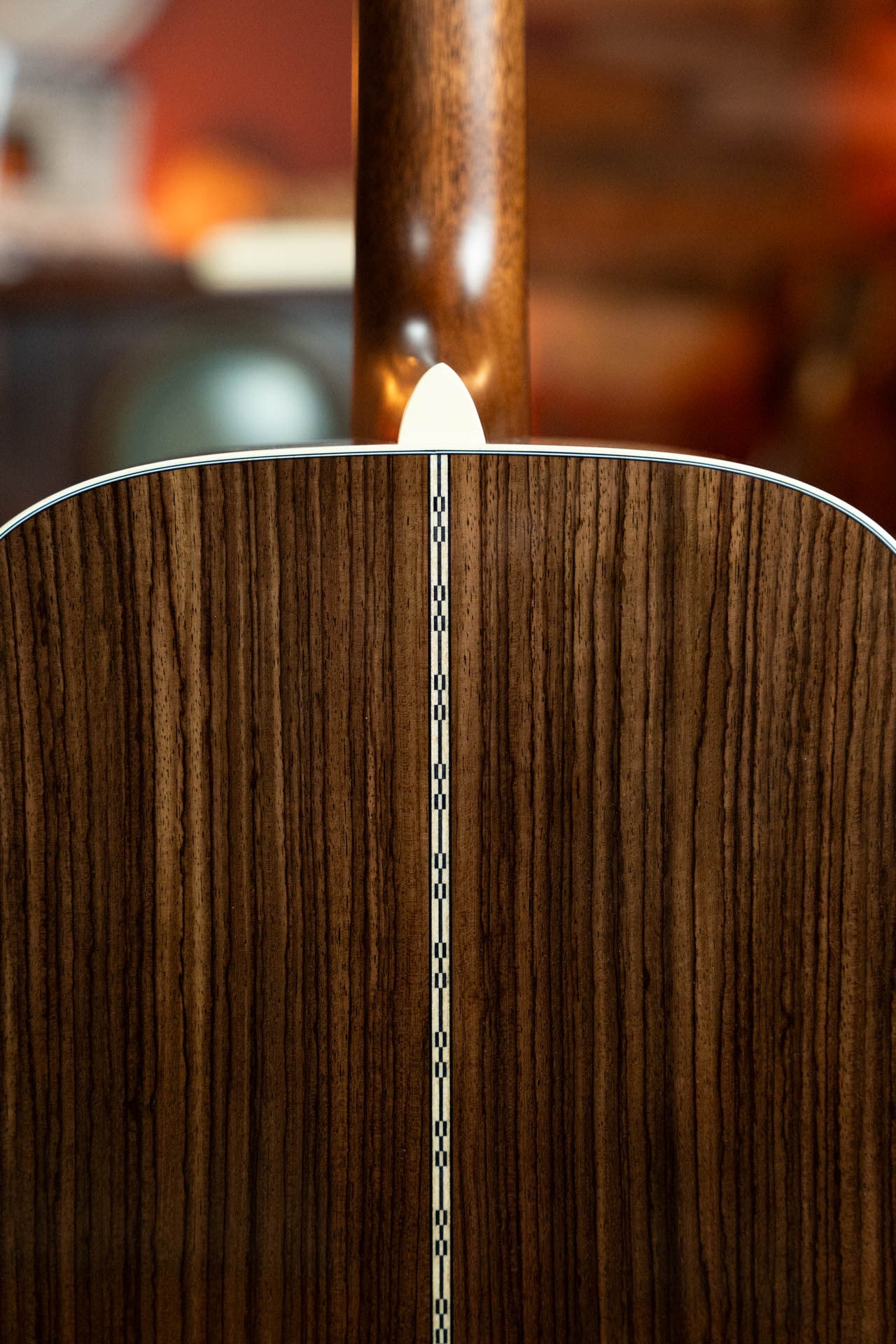 Close-up of the back of the *New 2025 Model* Martin & Co. D-28 Gloss Spruce/Indian Rosewood Dreadnought Acoustic Guitar #0650, highlighting dark Indian rosewood grain, a white center inlay, and part of the neck.