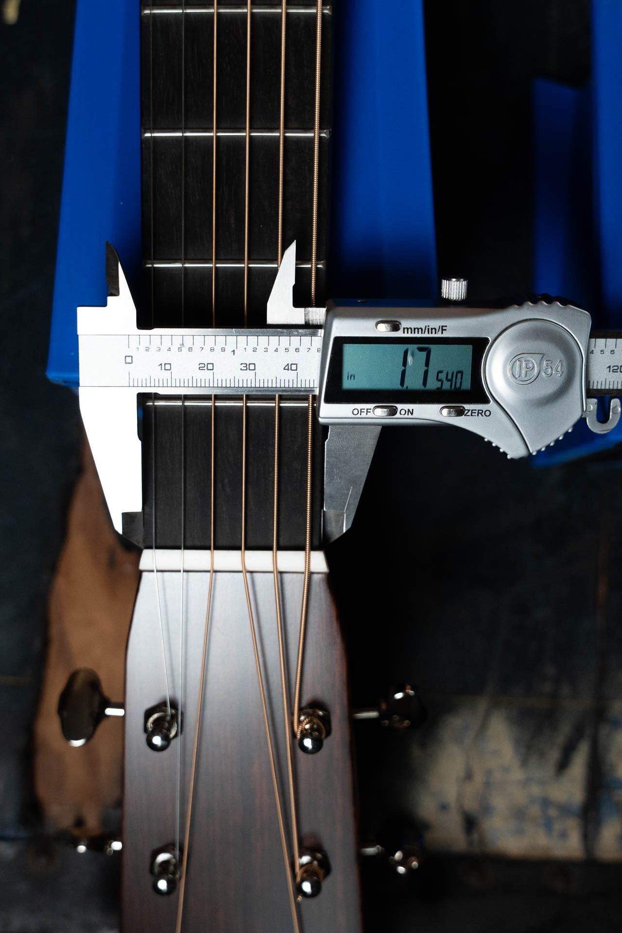 A digital caliper measures the width near the nut of a *New 2025 Model* Martin & Co. D-28 Gloss Spruce/Indian Rosewood Dreadnought Acoustic Guitar #0650 at 1.7540 inches. The 6-string neck is set against a blue background.