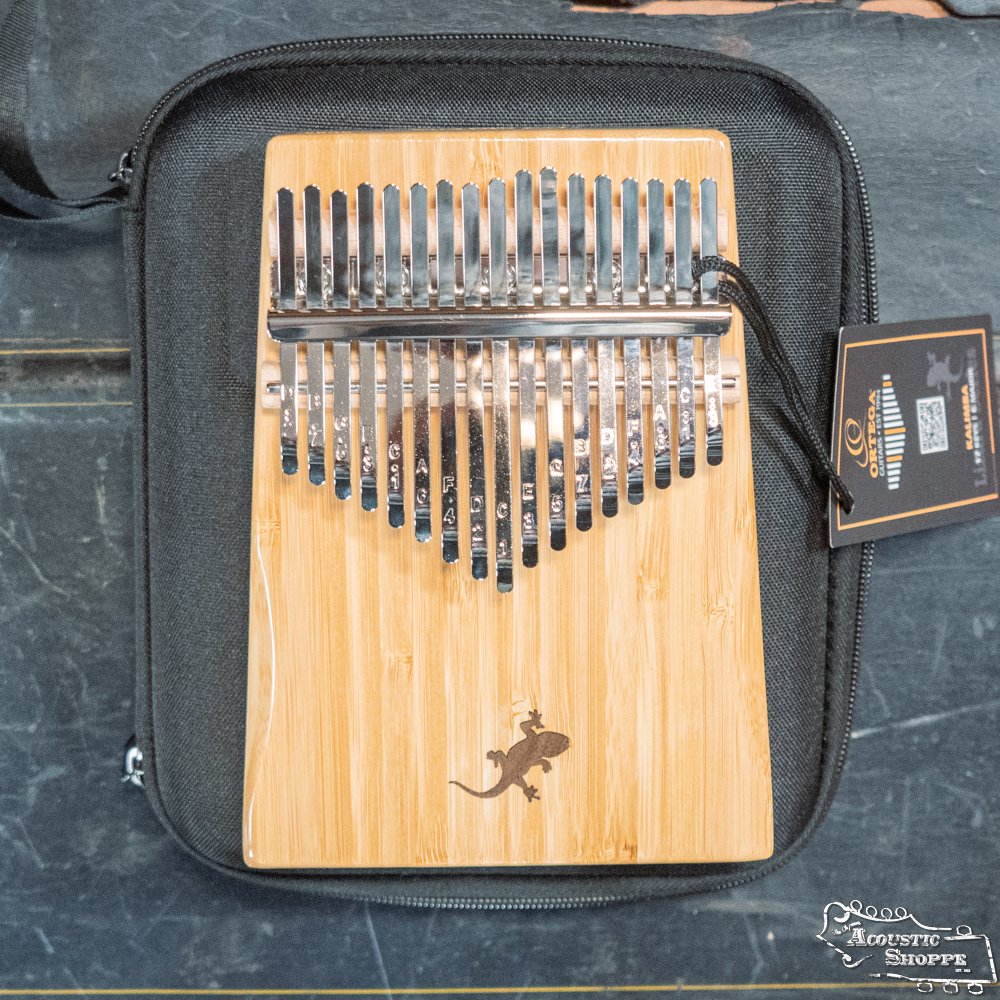 The Ortega OKB2 Lizard Series Solid Bamboo Kalimba by Ortega features 17 C major keys, a small lizard design, and comes with a black zippered case, all set against a dark background.