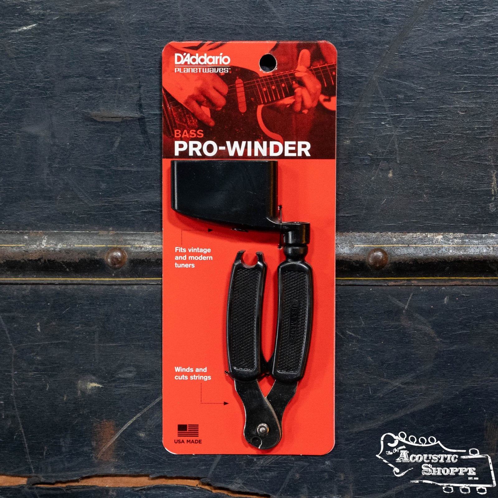 A D'Addario Bass Pro-Winder String Winder and Cutter DP0002B in red packaging is displayed on a dark textured surface, with The Acoustic Shoppe logo in the bottom right corner.