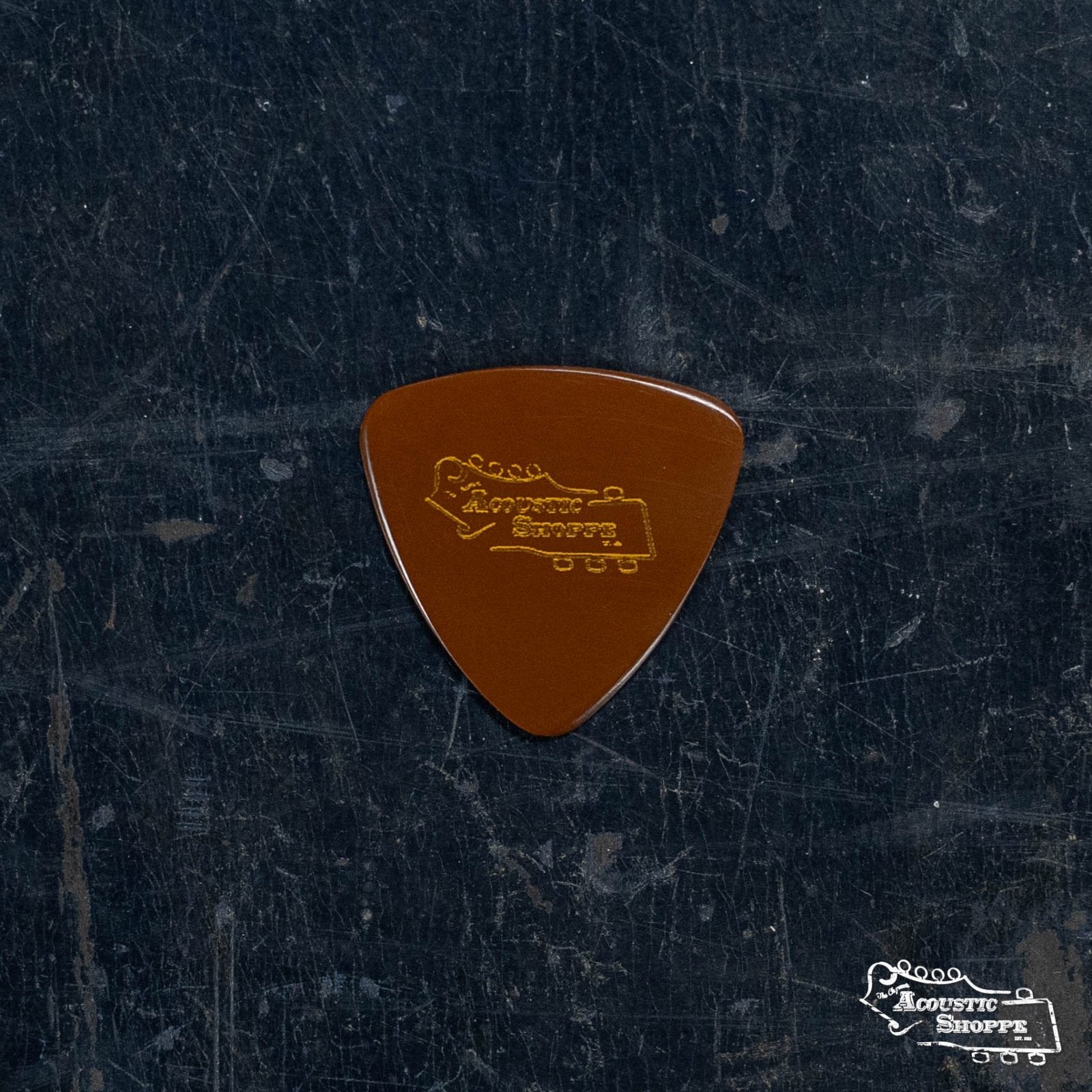 A BlueChip Picks (STP40) by BlueChip rests on a dark, textured surface—ideal for musicians seeking high-quality guitar picks.