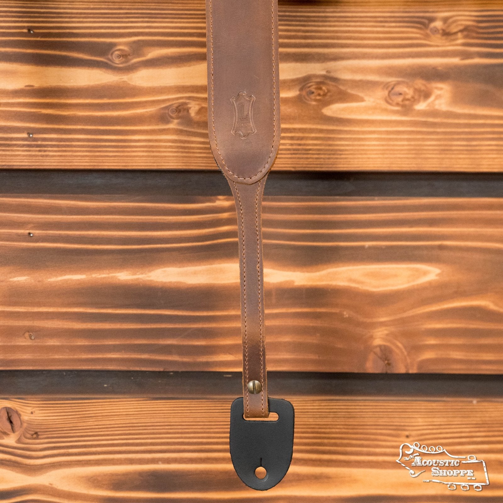 The Levys Leather Banjo Master Series PMB32GF-BRN Padded Butter Leather Banjo Strap in brown features a black end piece, natural polished finish, and an embossed emblem for added style.