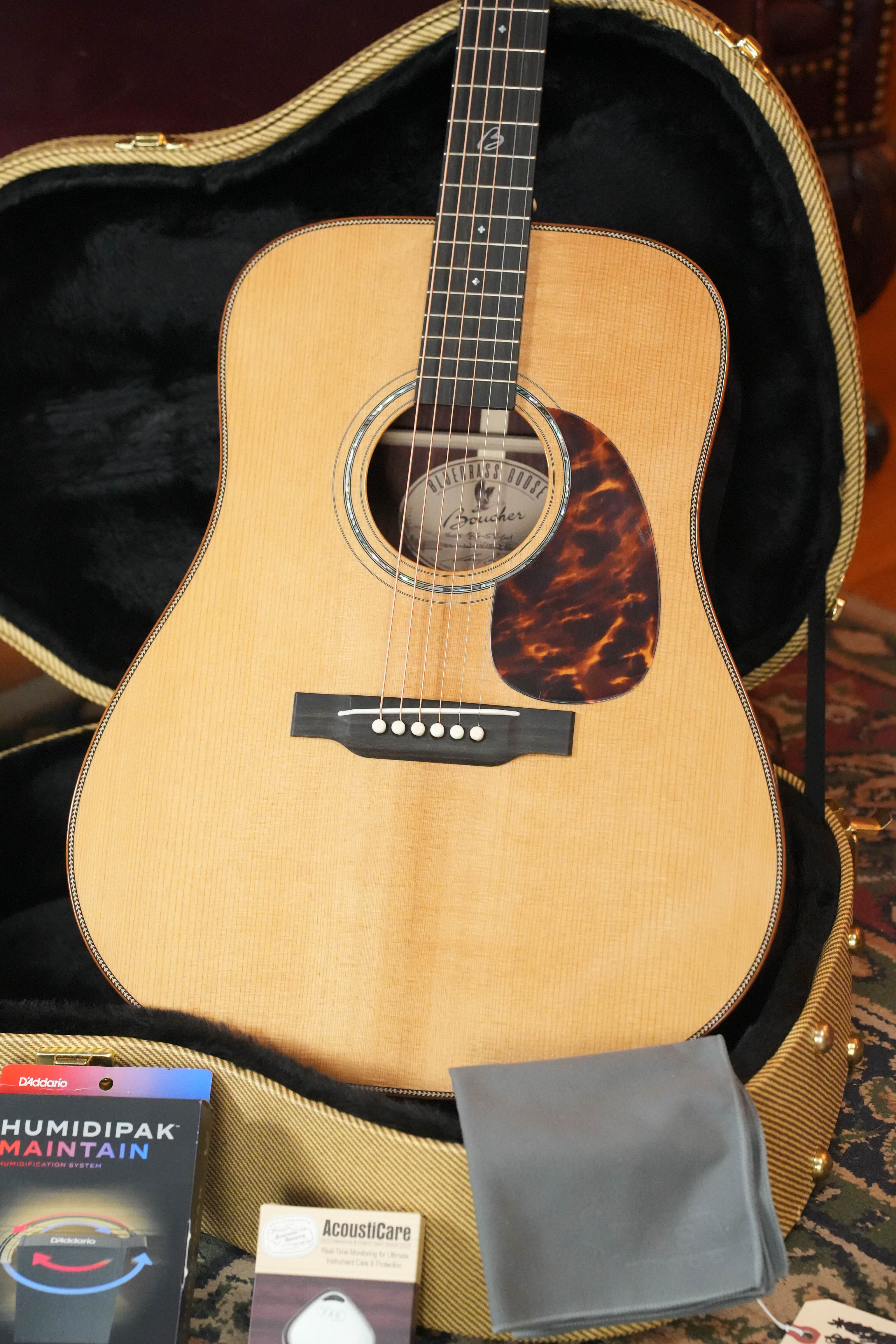 A brand-new Boucher Guitars *Stage Ready* BG-52-GM Torrefied Adirondack/Rosewood Bluegrass Goose Gold Master Pack Dreadnought Acoustic Guitar #1415 sits in an open hard case, with a tortoiseshell pickguard, gray cloth, two maintenance packs, and a humidity control pack.