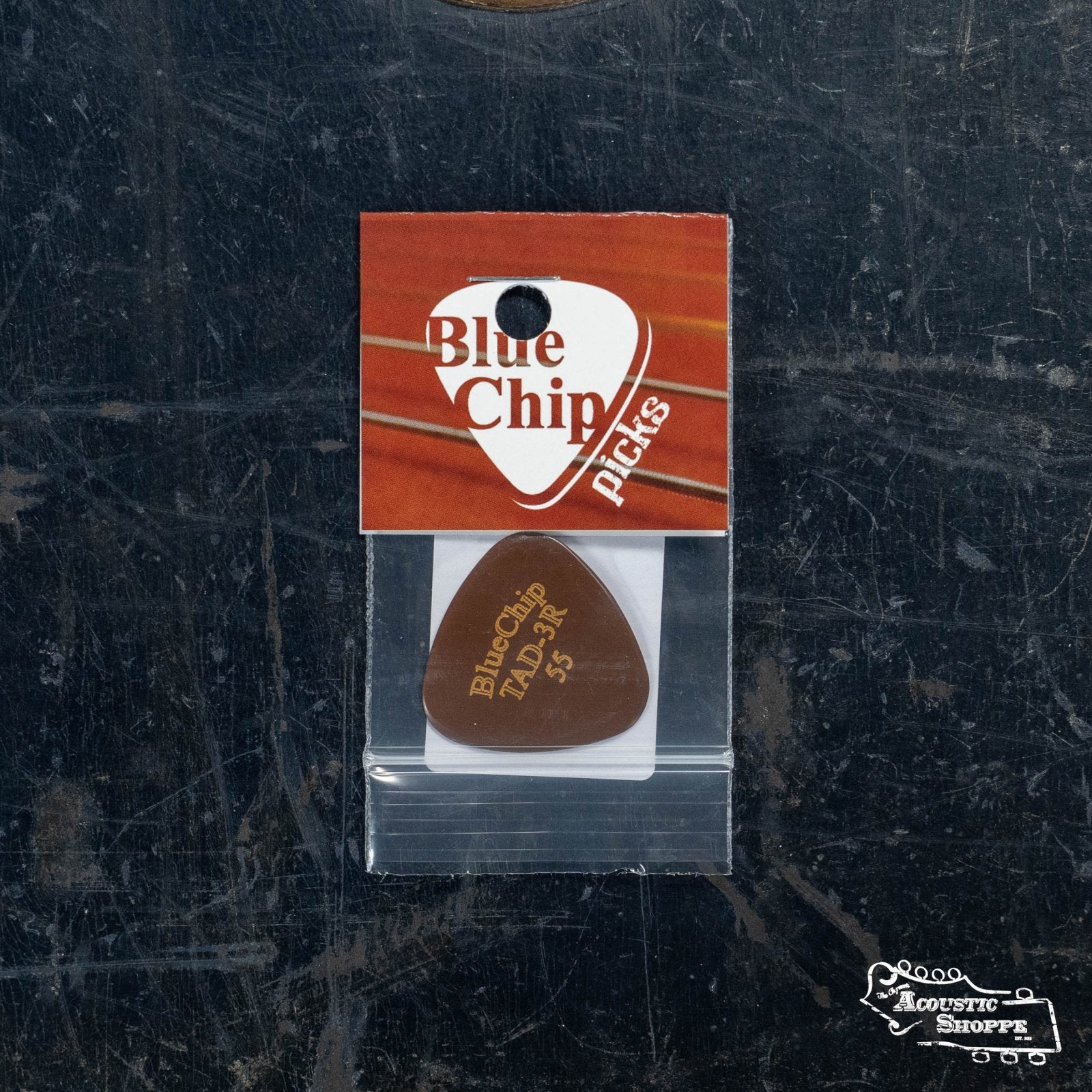 A BlueChip Pick (TAD55-3R) in a clear plastic sleeve, attached to a brown and white BlueChip branded card, is shown on a dark, textured surface with the Acoustic Shoppe logo in the lower right corner.