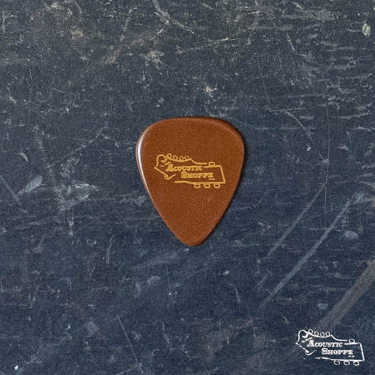 A BlueChip Picks (TD40) brown teardrop guitar pick with a yellow BlueChip logo rests on a dark, textured surface. Perfect for acoustic music accessories, the same logo appears in the lower right corner of the image.