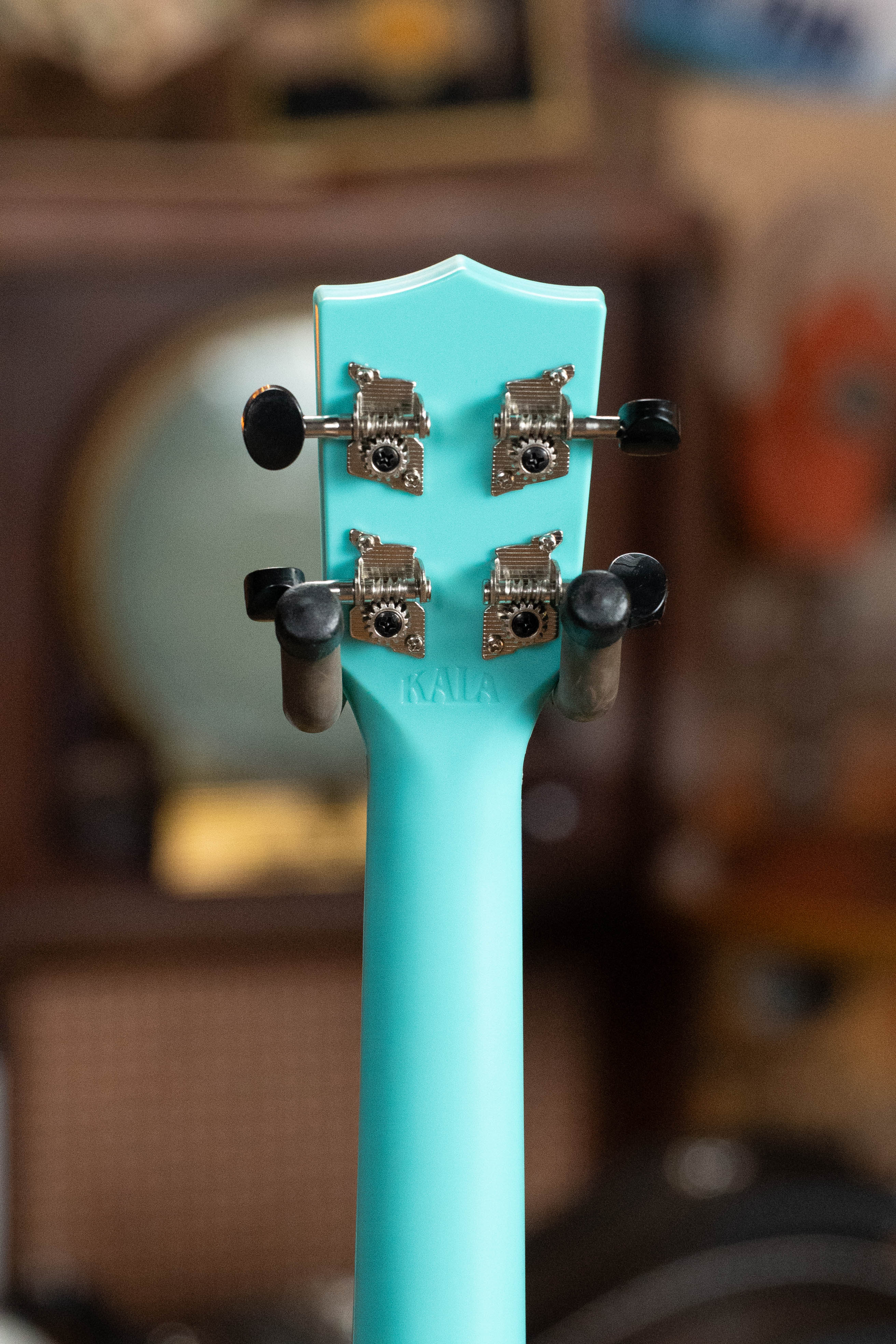 Aqua mist blue soprano ukulele neck and headstock with silver tuning pegs on a blurred background. - The Waterman Aqua Mist Glow-In-The-Dark Soprano Recycled Ukulele - Kala Brand - Default Title