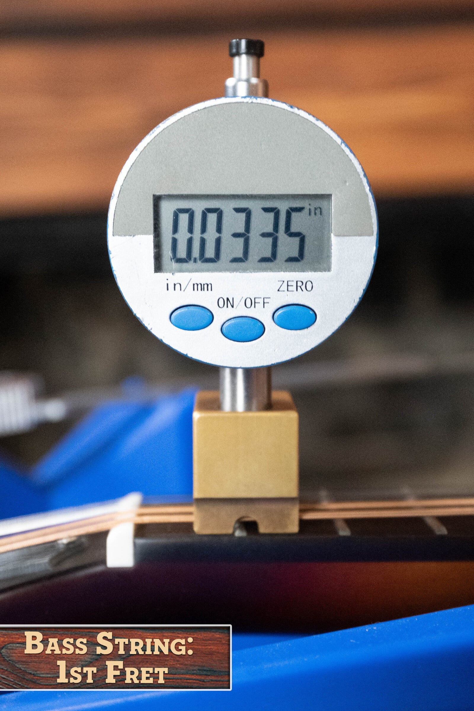 A digital gauge shows a bass guitar string at the 1st fret as 0.0335 inches, with a label reading Bass String: 1st Fret, similar to checking action on The Loar LM-310F-BRB Honey Creek F-Style Brownburst Mandolin #0069 by The Loar.