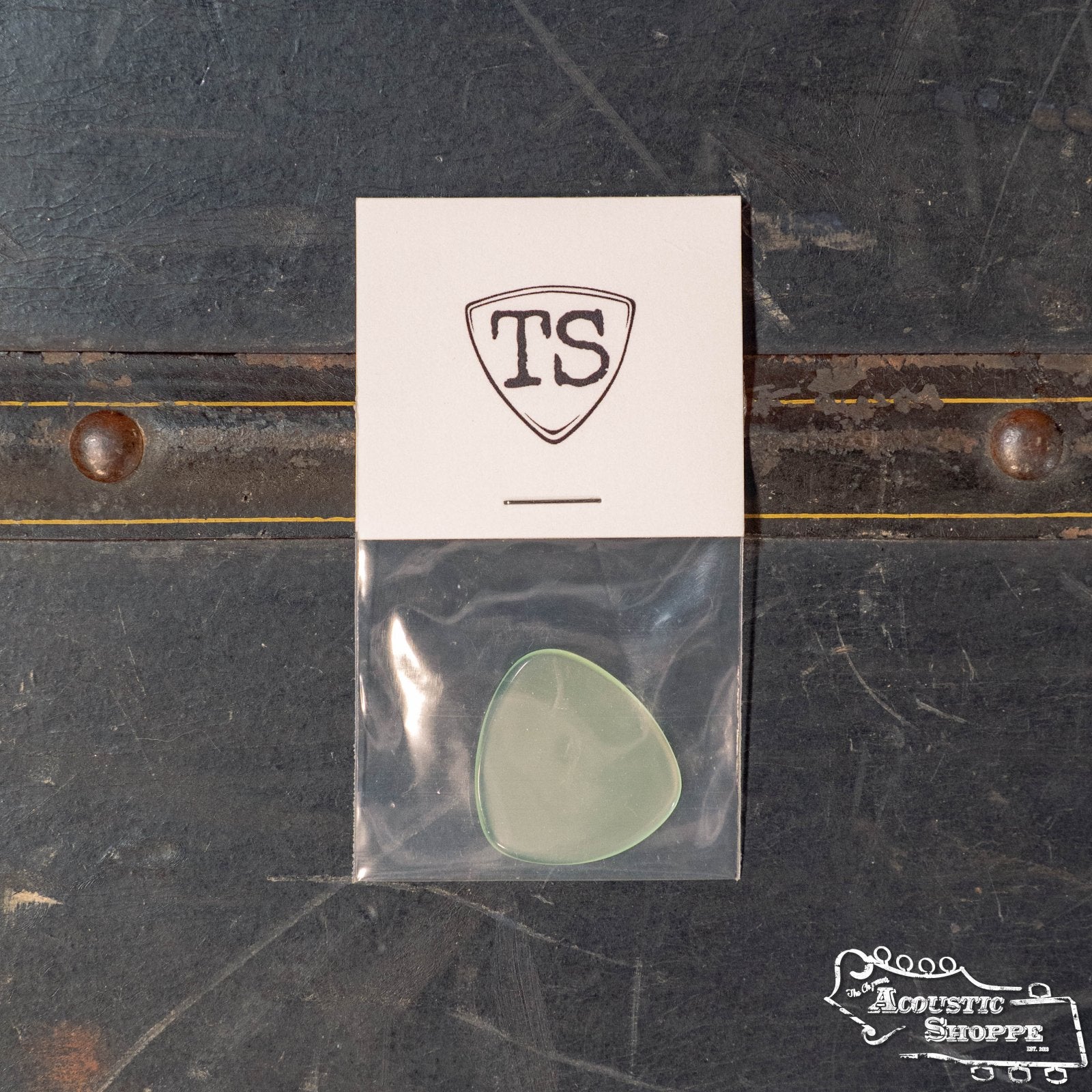 A translucent ToneSlabs Oh Seven Rounded Jazz Guitar Pick (1.3 mm), packaged in a clear bag with a TS card, rests on a dark surface. The Acoustic Shoppe logo appears at the bottom right, emphasizing this premium ToneSlabs accessory.