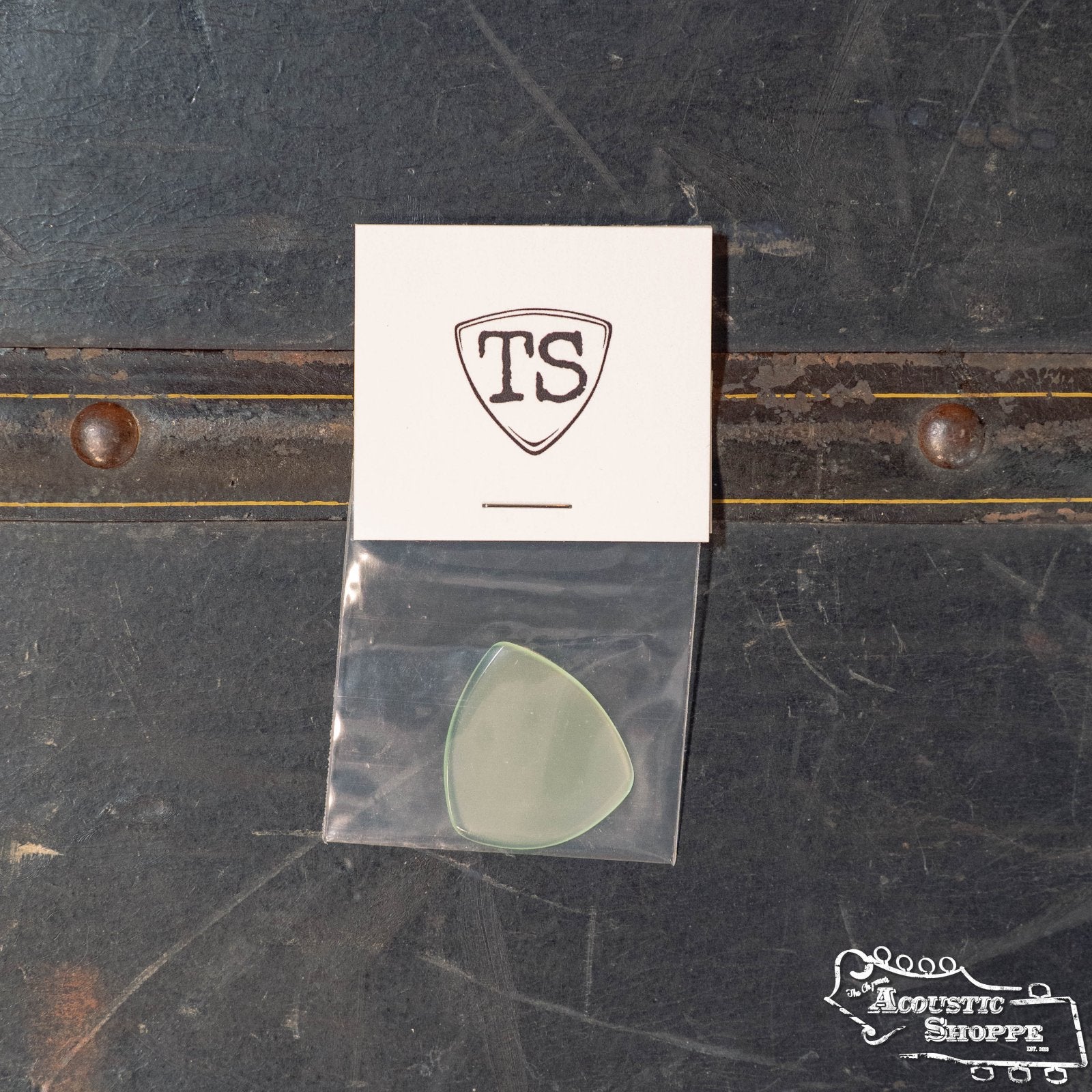 The ToneSlabs Oh Eight Pointed Jazz Guitar Pick (1.3 mm), a translucent tortoise shell alternative, comes in a plastic bag with a TS card, set on a dark, worn surface with the Acoustic Shoppe logo in the corner.
