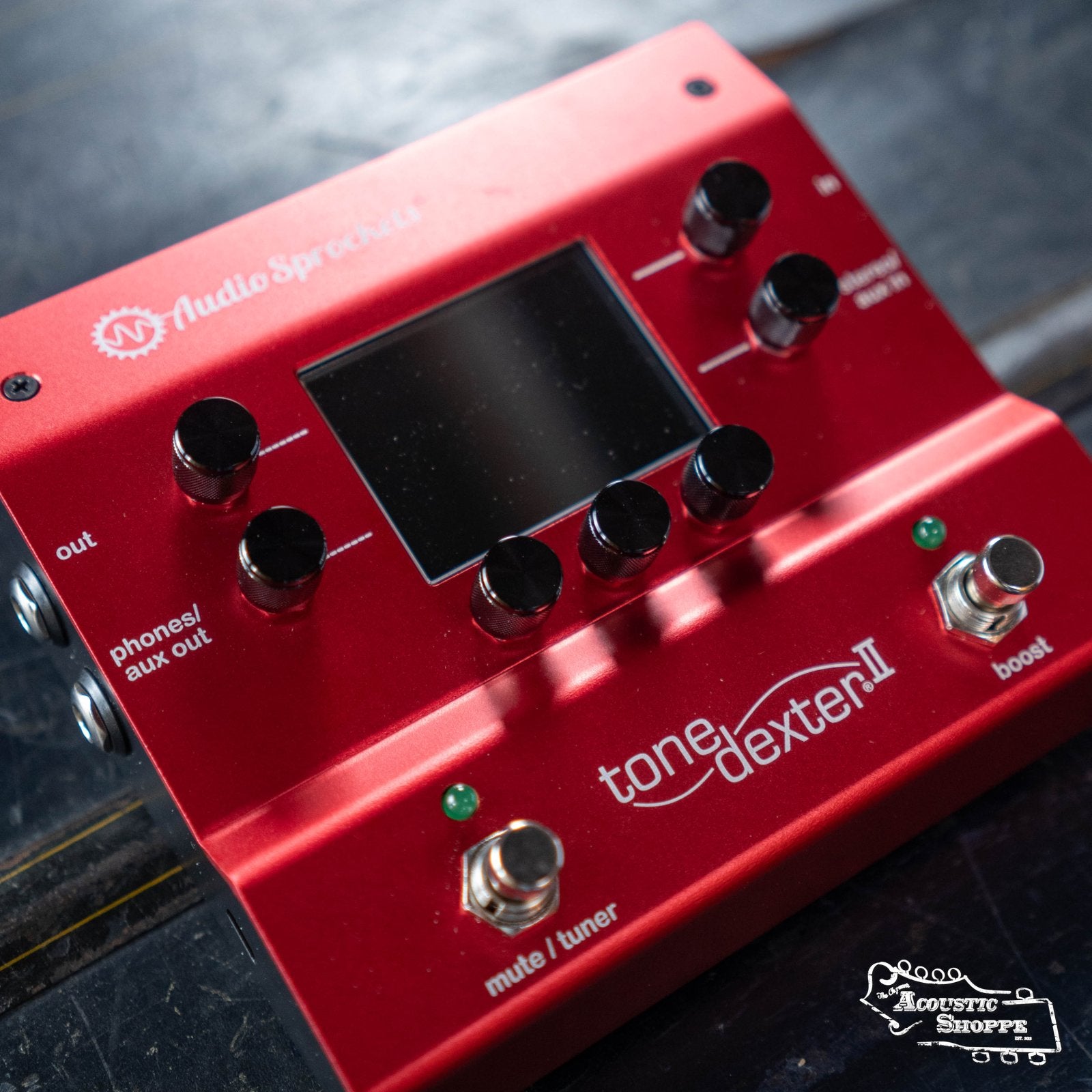 The Audio Sprockets ToneDexter II is a red device with black dials and buttons, designed as an acoustic instrument preamp to enhance pickup sound quality.