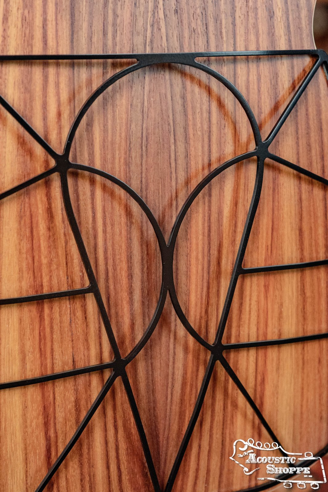 Close-up of a wooden surface with a black, geometric art-deco design. The Acoustic Shoppe logo appears in the corner—a stylish backdrop for showcasing Tone-Gard Dreadnaught Guitar D-Gard by Tone-Gard, designed to enhance your guitars tone.