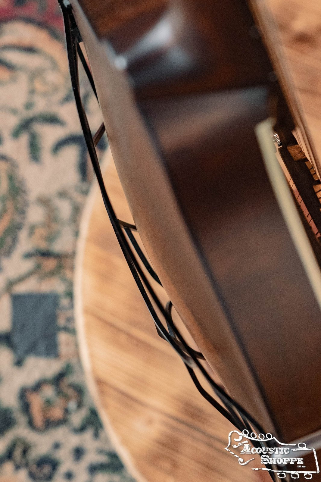 Overhead view of an acoustic guitar on a wooden stand atop a patterned rug. The Tone-Gard OM-Gard Octave Mandolin by Tone-Gard is displayed nearby, with the Acoustic Shoppe logo visible in the lower right corner.