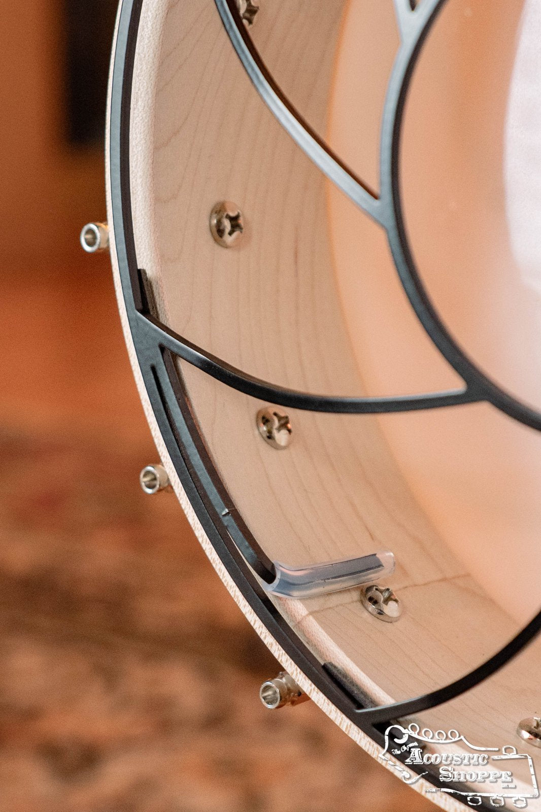 Close-up of the inside rim of a Tone-Gard Open Back Banjo (12) by Tone-Gard, highlighting metal hardware and wooden body details. The Acoustic Shoppe logo is visible in the lower right corner.