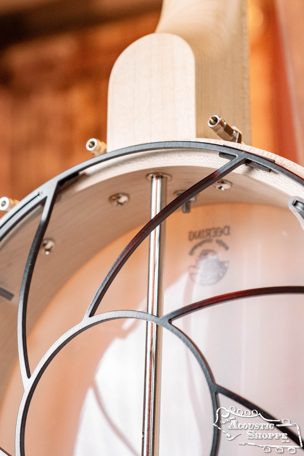 Close-up of the Tone-Gard Open Back Banjo (12) by Tone-Gard, highlighting the wooden frame, metal brackets, and plastic head—offering protection similar to a mandolin back protector. The Acoustic Shoppe logo appears in the bottom right corner.