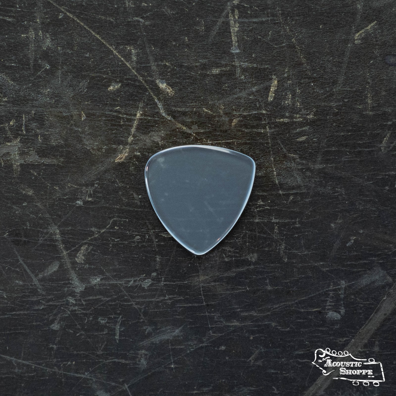 A single transparent ToneSlabs Mini Tri 1Round Guitar Pick (1.4mm) rests on a dark, scratched surface. The Acoustic Shoppe logo appears in the lower right corner, emphasizing this unique ToneSlabs guitar accessory.